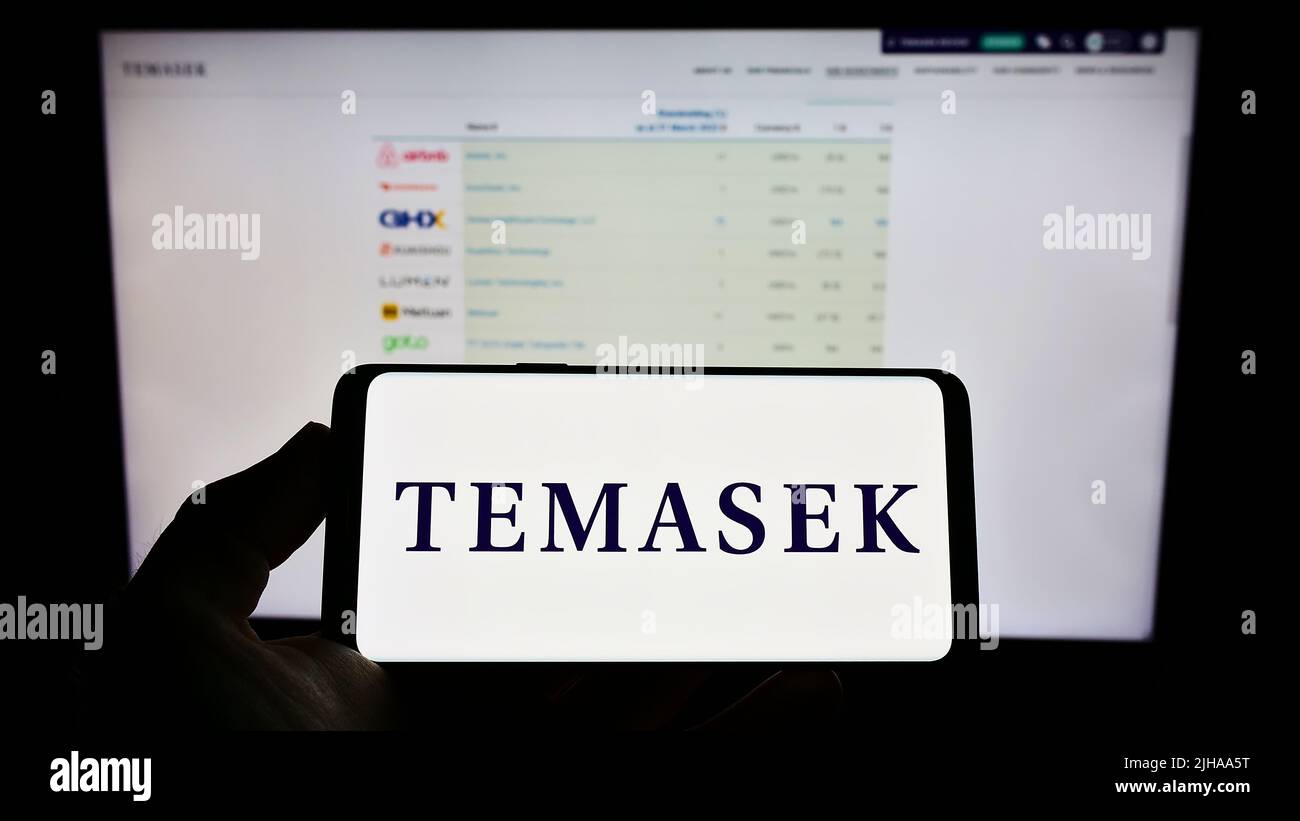 Personne tenant un smartphone avec le logo de la société Temasek Holdings Private Limited à l'écran devant le site Web. Mise au point sur l'affichage du téléphone. Banque D'Images