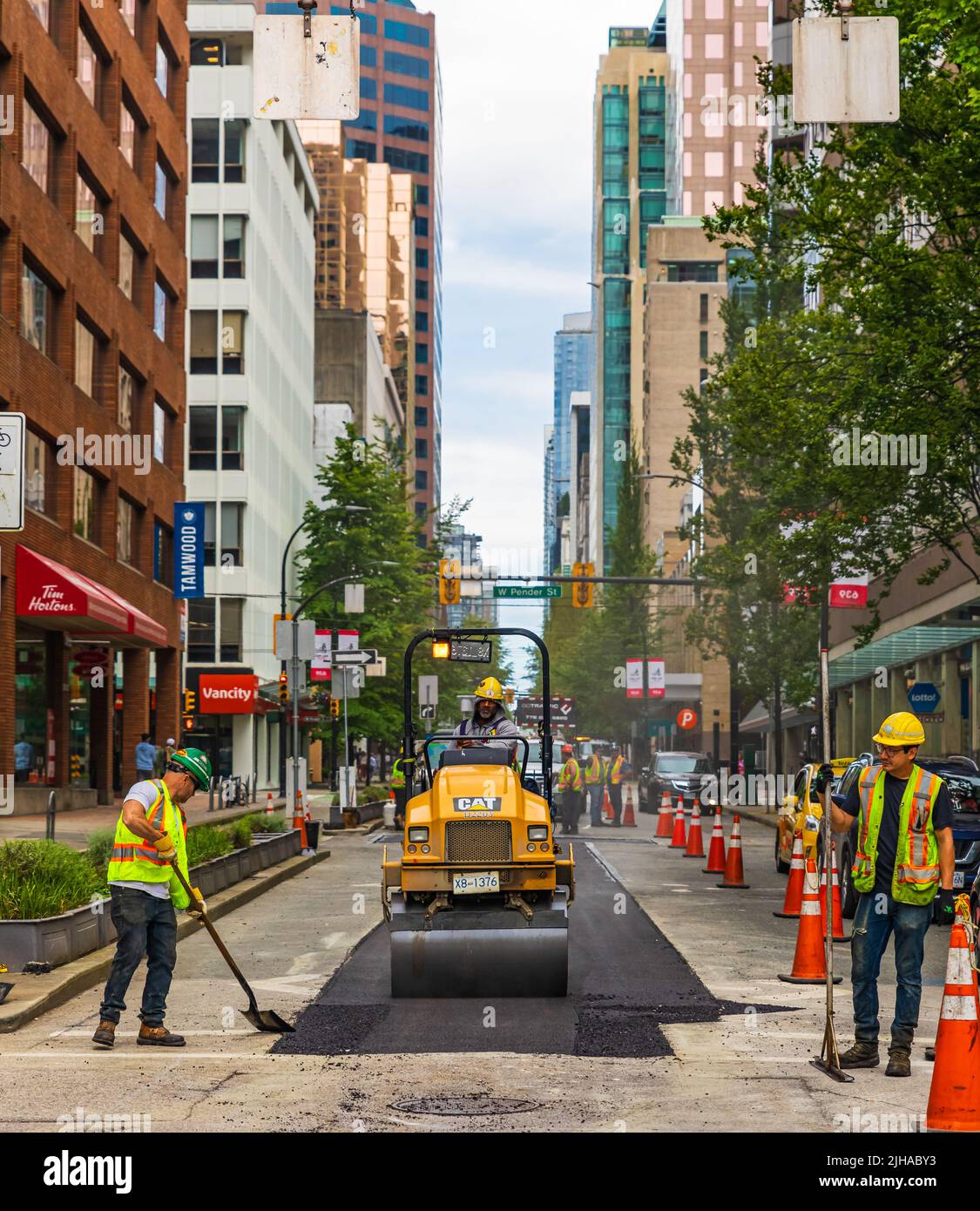 Une équipe de travailleurs a mis l'asphalte chaud sur une route. Travailleurs de la construction routière avec des pelles en uniformes de protection. Travaux de construction routière dans une ville-1 juillet Banque D'Images