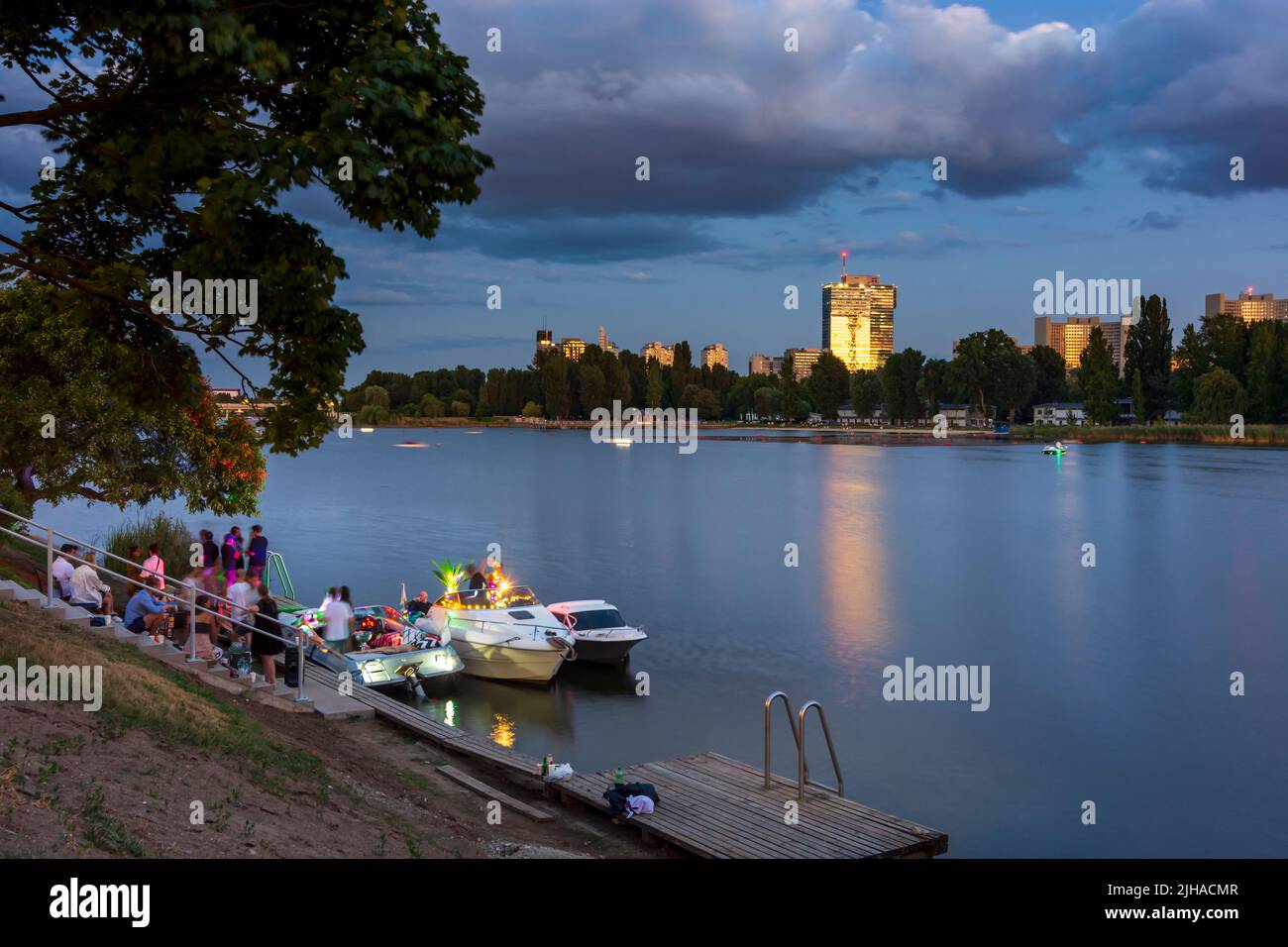 Wien, Vienne: lac oxbow Alte Donau (Vieux Danube), coucher de soleil, fête privée sur les bateaux, Tour IZF en 22. Donaustadt, Wien, Autriche Banque D'Images