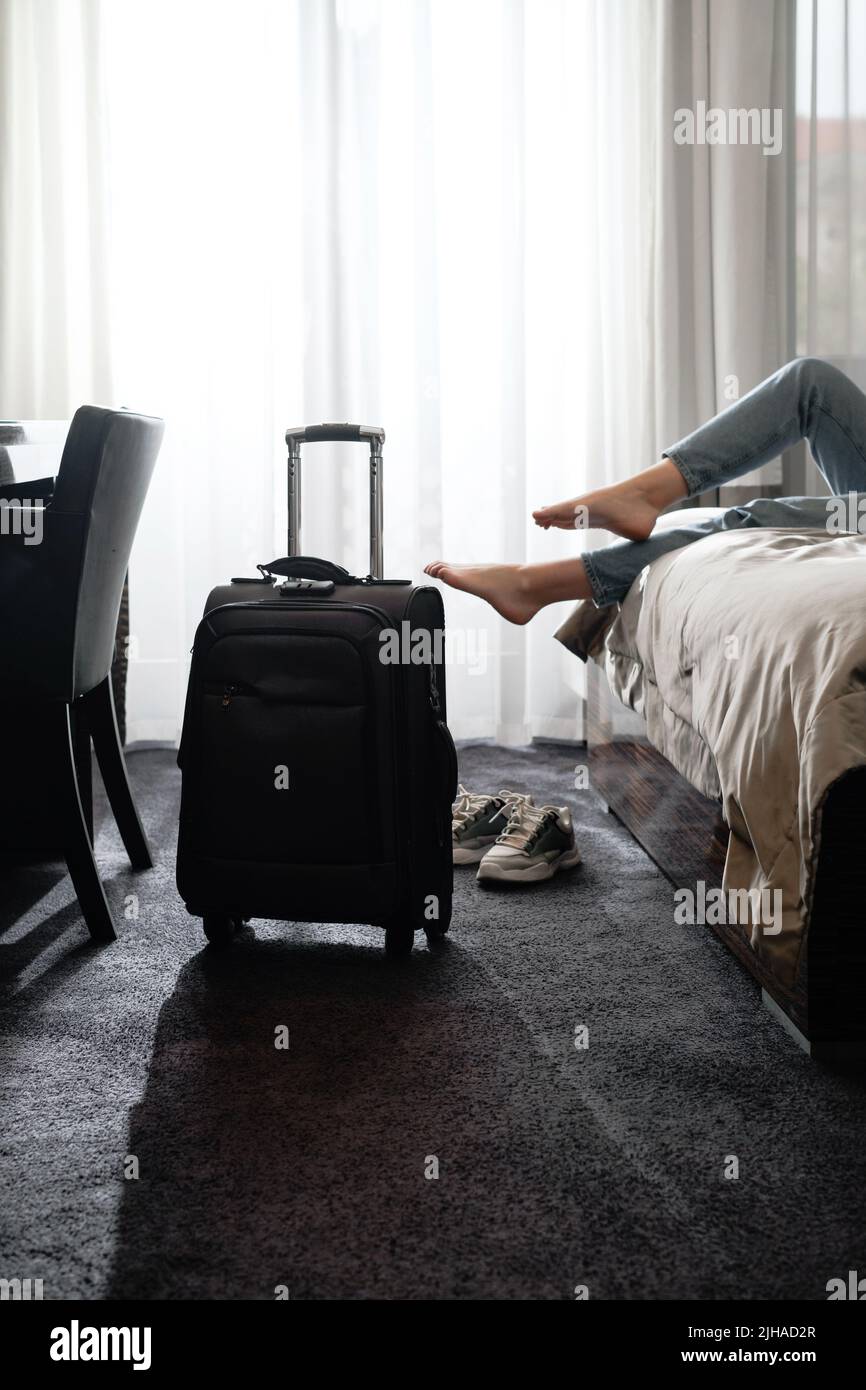 femme prenant des chaussures dans une chambre d'hôtel sur le lit. Touriste se détendre dans la chambre d'hôtel après avoir voyagé avec une valise. Femme ayant le repos après longtemps Banque D'Images