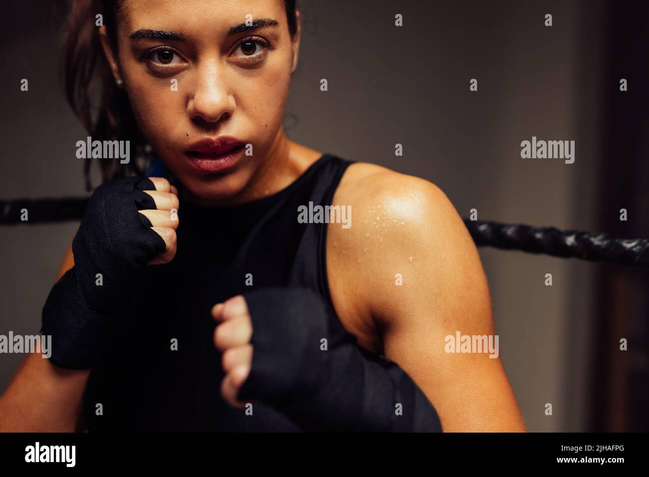 Femme Martial regardant la caméra en position de combat à l'intérieur d'un anneau de boxe. Entraînement de boxeur féminin dans un gymnase de boxe. Banque D'Images Femme Martial regardant la caméra en position de combat à l'intérieur d'un anneau de boxe. Entraînement de boxeur féminin dans un gymnase de boxe. Banque D'Images
