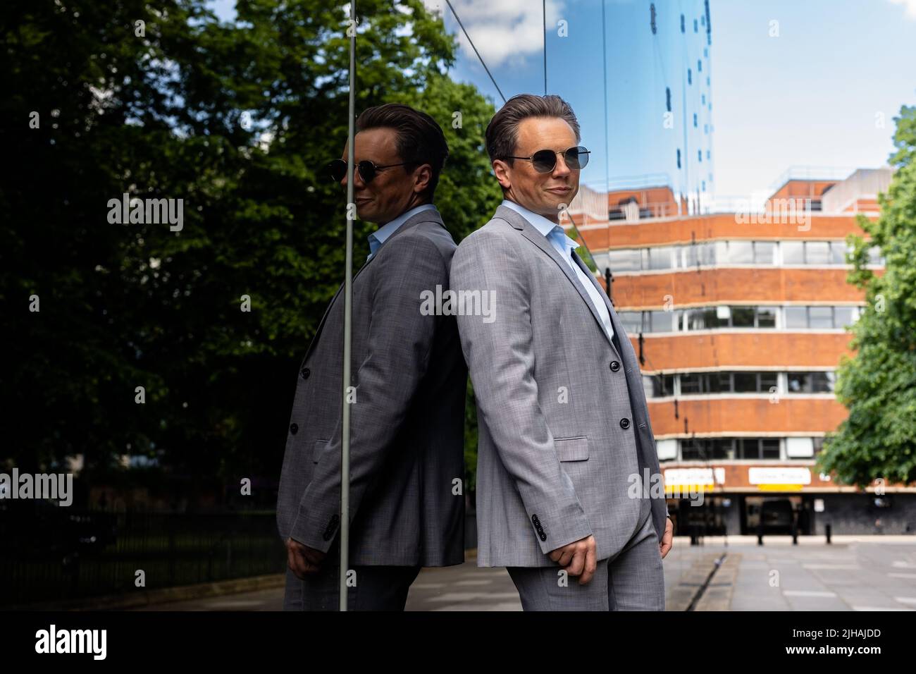 Un beau homme d'affaires dans un costume gris et des lunettes de soleil dans un environnement urbain Banque D'Images