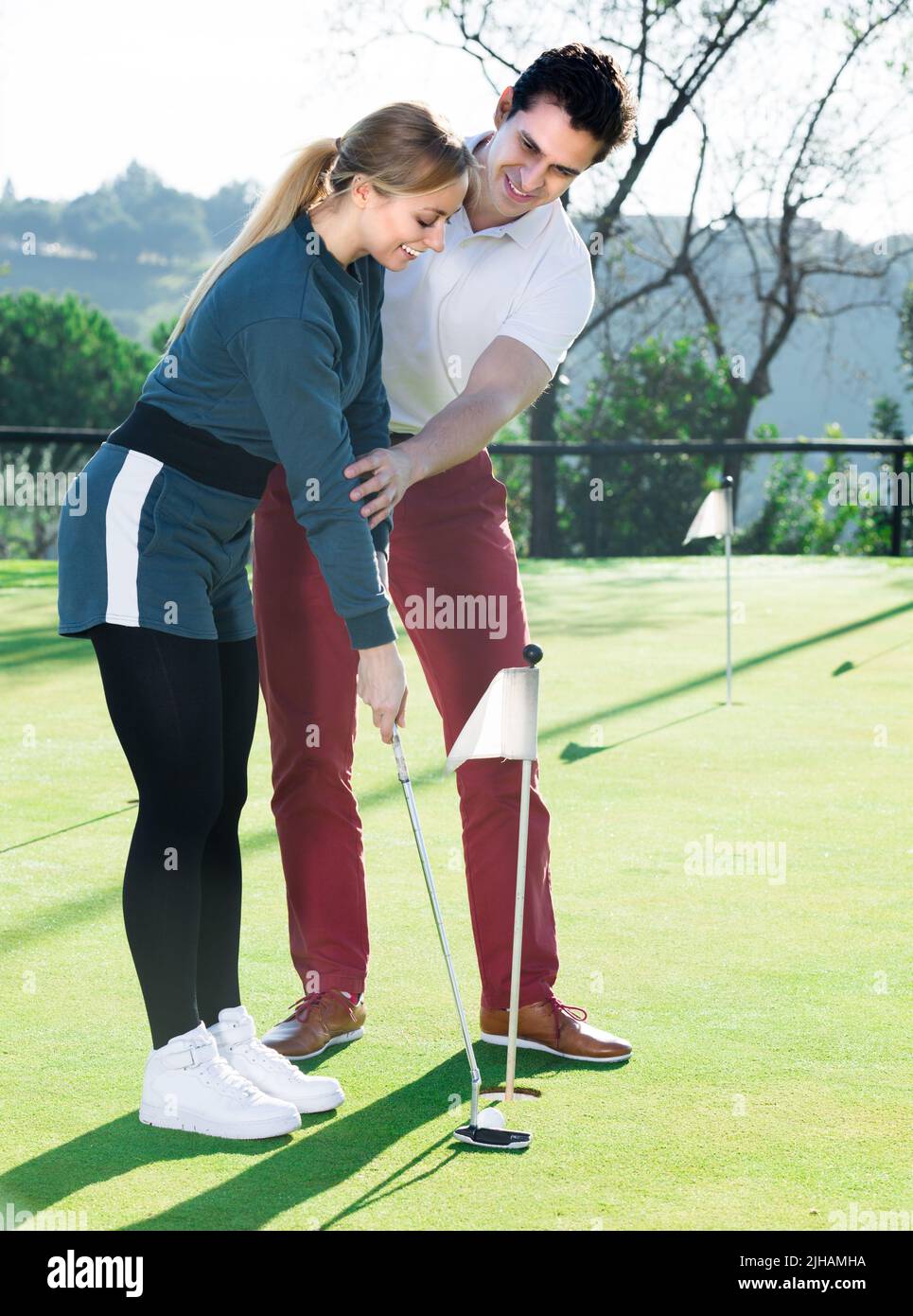 Le jeune homme forme une femme pour jouer au golf Banque D'Images