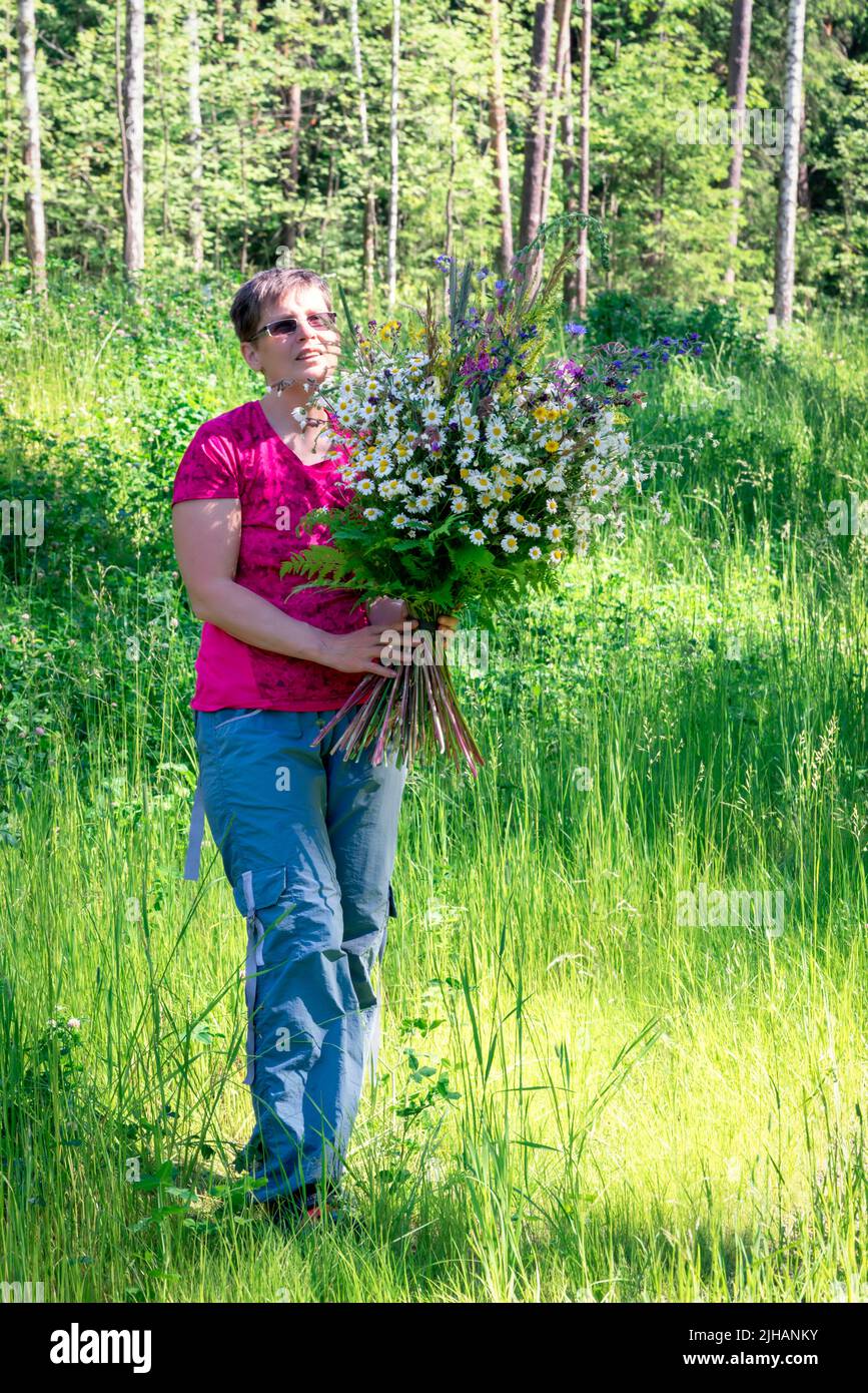 Femme tenant un énorme bouquet de fleurs sauvages, portrait pleine longueur. Banque D'Images