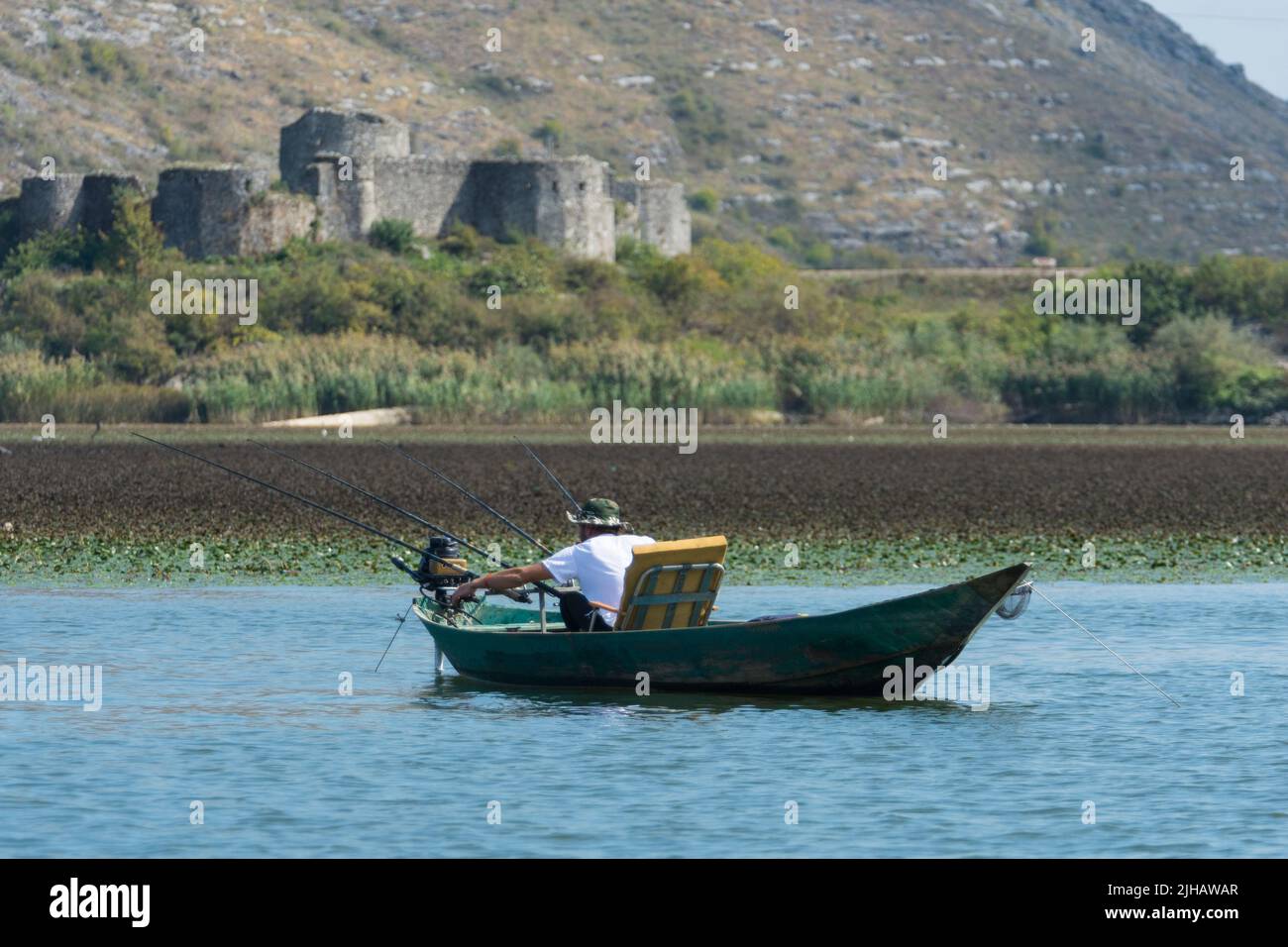 Pêcheur dans son bateau sur le lac Skadar au Monténégro. Forteresse médiévale en arrière-plan Banque D'Images