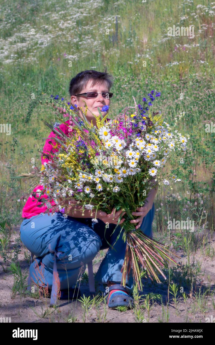 portrait d'une femme souriante heureuse avec un bouquet de fleurs sauvages Banque D'Images