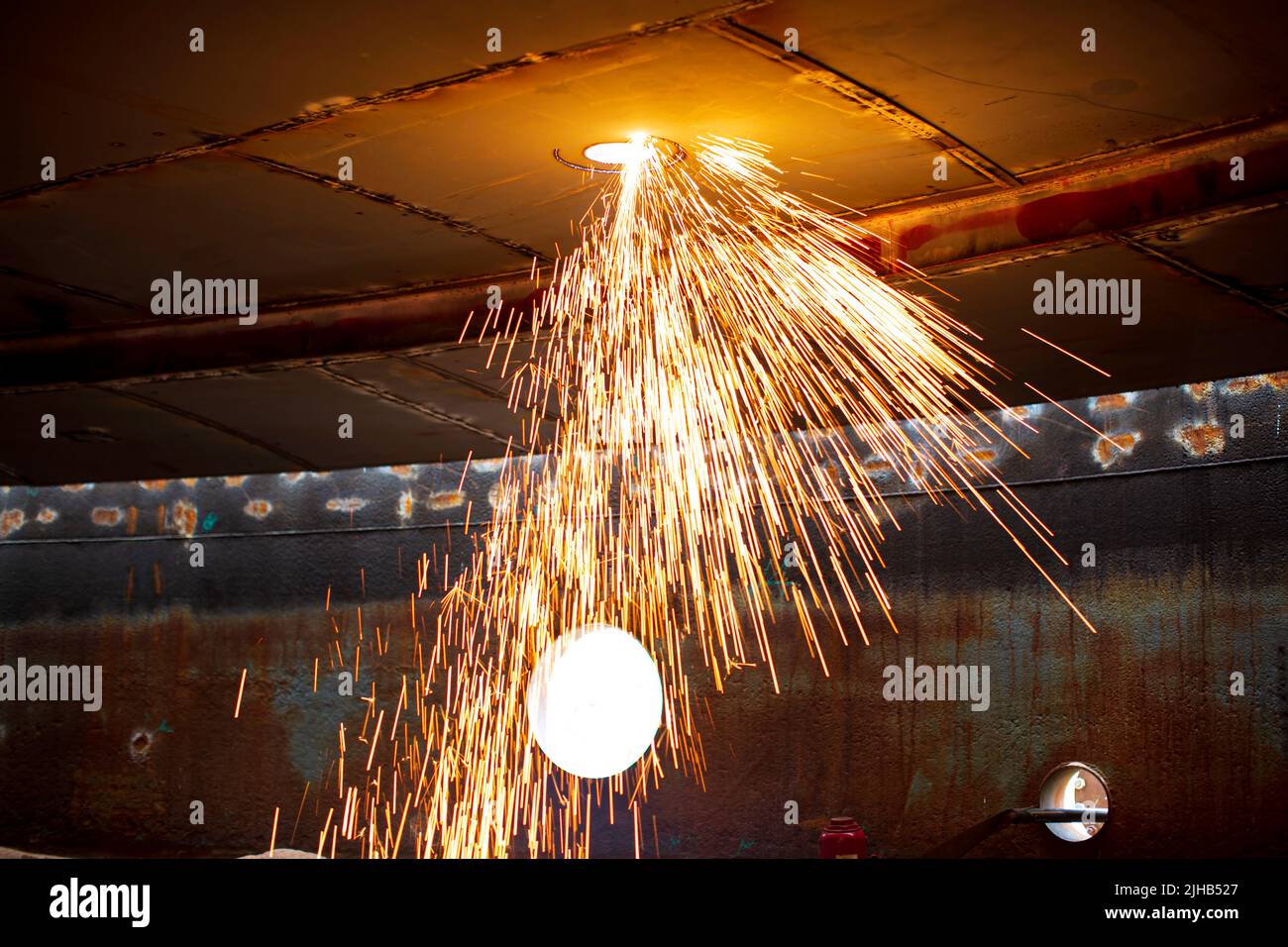 Étincelle de découpe de métal sur la plaque en acier du toit de la cuve avec flash de découpe de lumière dans un espace confiné. Banque D'Images