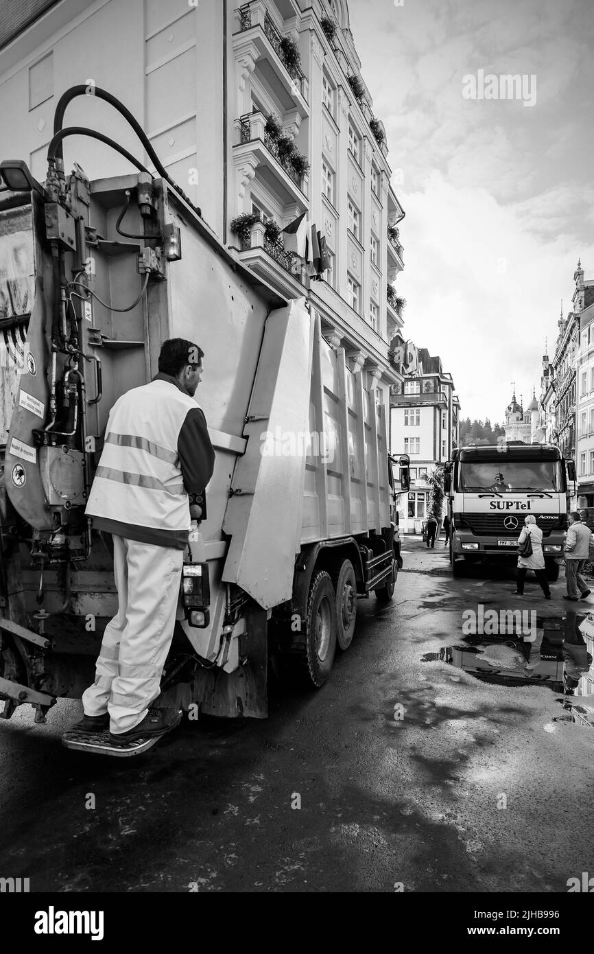 Karlovy Vary, Tchéquie - 5 octobre 2009 : collecteur d'ordures sur le camion à ordures de Karlovy Vary. Photographie urbaine en noir et blanc Banque D'Images