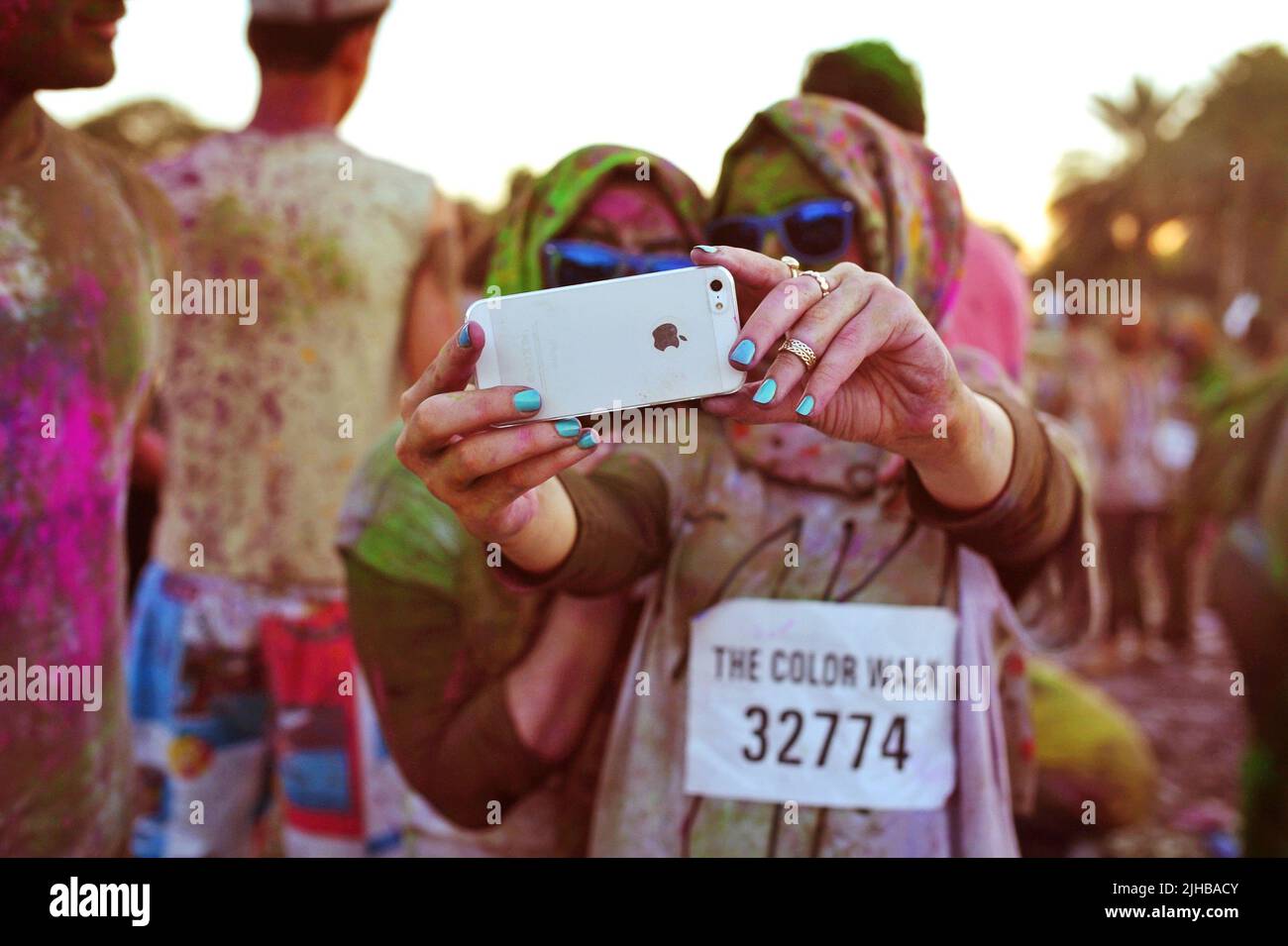 Deux amis arabes, des femmes portant des Hijabs, prennent un iPhone selfie d'eux-mêmes recouvert de poudre colorée à la Color Walk à Dubaï, Émirats arabes Unis Banque D'Images