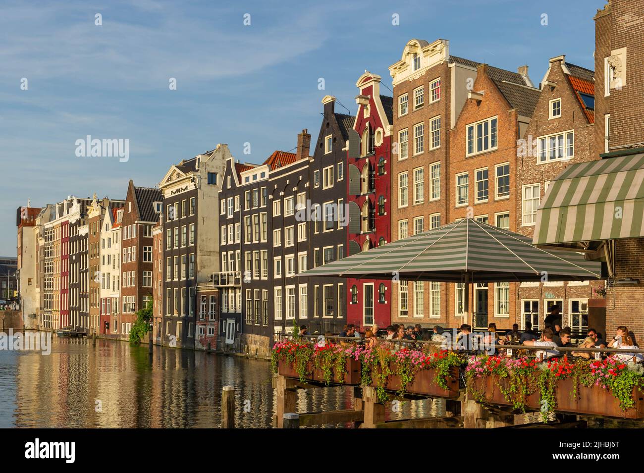 Dîner sur le Damrak, Amsterdam au coucher du soleil, surplombant l'eau avec des maisons hollandaises en bord de canalside en arrière-plan Banque D'Images