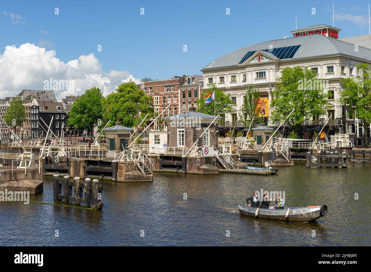 Bateaux passant par les écluses Amstel (Amstelsluizen) Amsterdam par une journée ensoleillée avec le Théâtre Royal Carre en arrière-plan Banque D'Images
