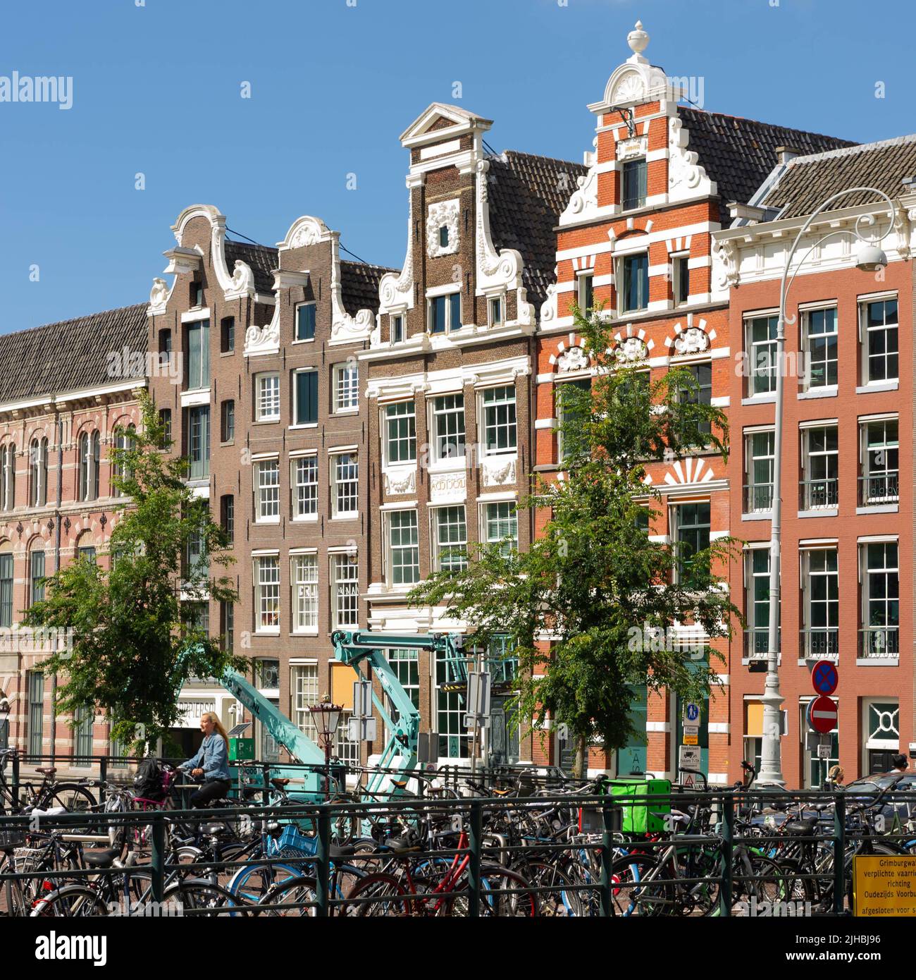Maisons d'Amsterdam au coucher du soleil avec des vélos sur un pont en premier plan Banque D'Images