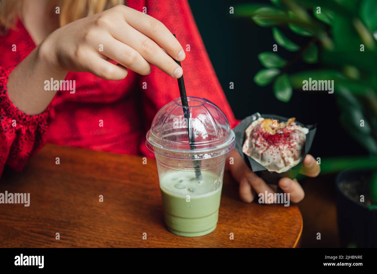 Latte au matcha glacé et gros gâteau dans un café entre les mains des femmes. Banque D'Images