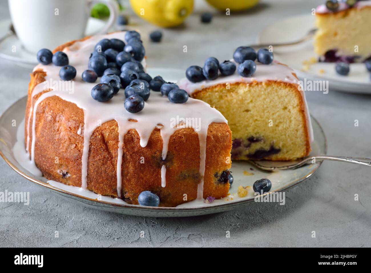 Gâteau aux myrtilles au citron recouvert de sucre doux et de baies, servi avec du café Banque D'Images