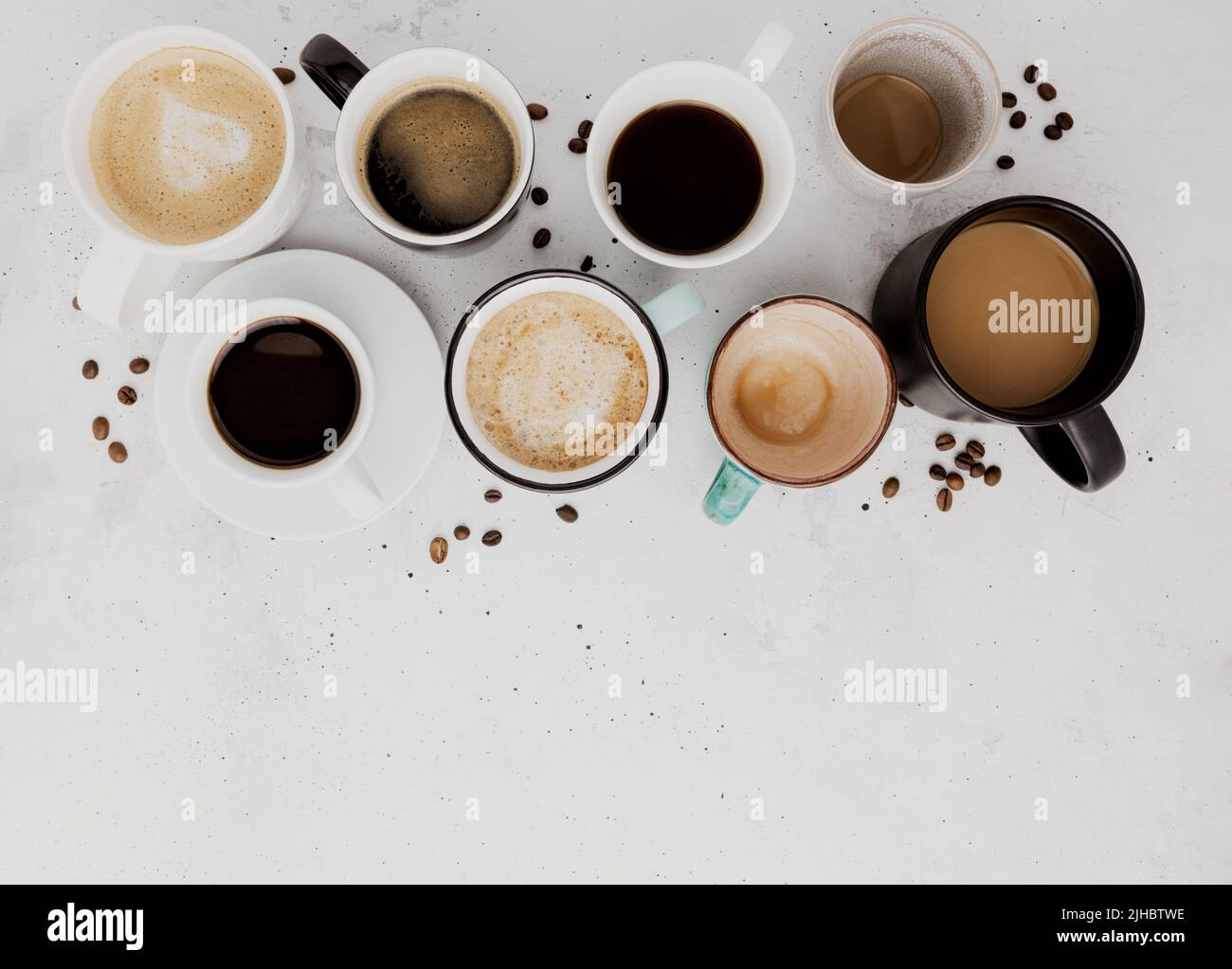 Vue de dessus sur un plat avec de nombreuses différentes compositions de tasses à café pleines et vides sur fond de béton blanc gris. Variété de disposition de la collection de tasses à thé. Grains de café séchés. Espresso, latte, americano Banque D'Images