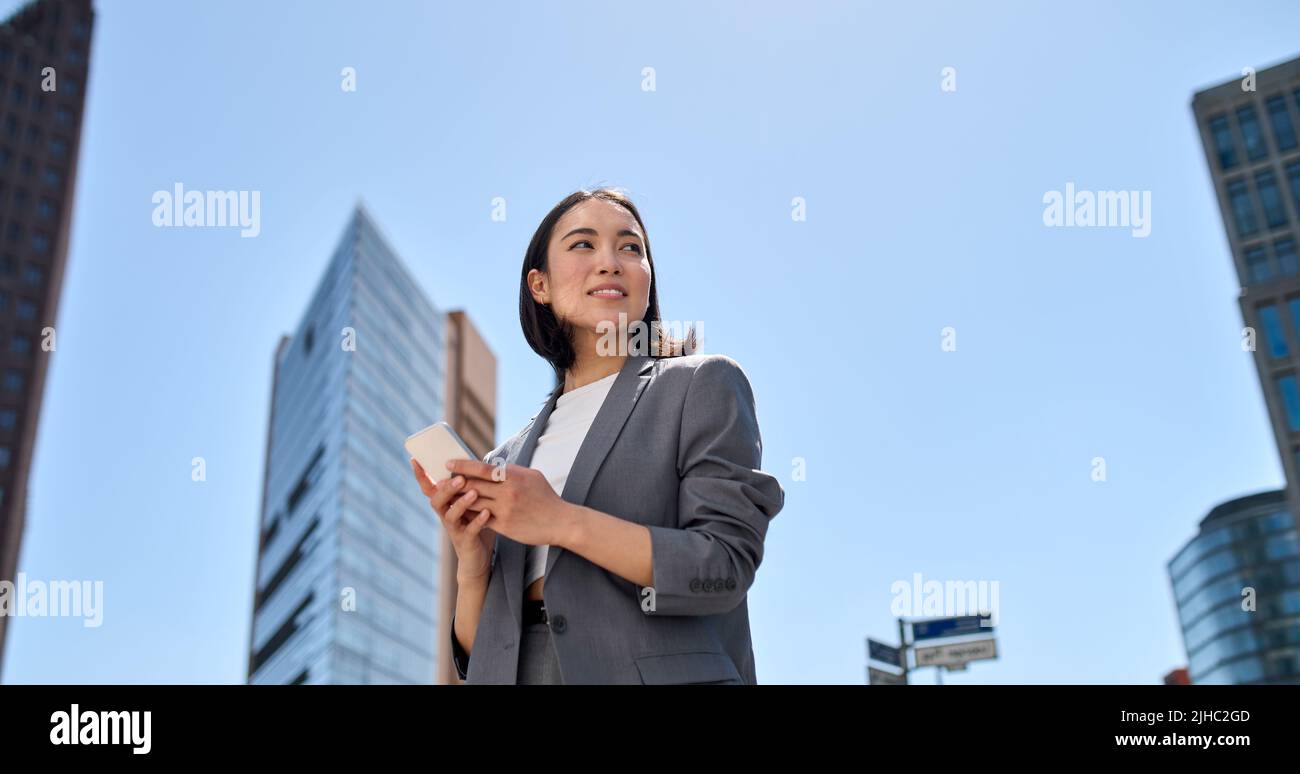 Jeune femme d'affaires asiatique magnifique utilisant un smartphone dans la rue de la ville. Banque D'Images