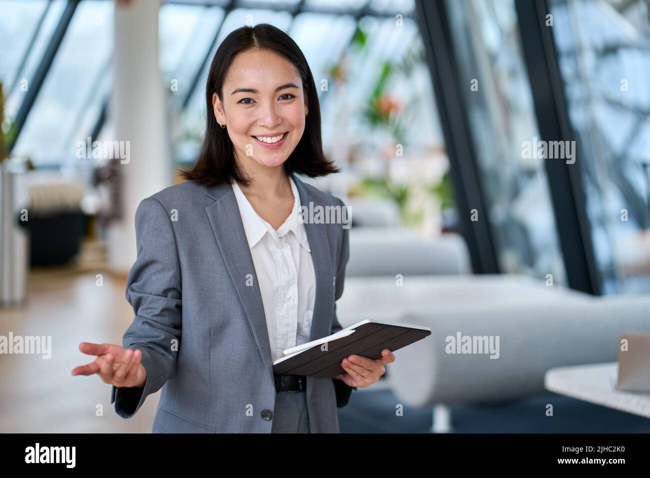 Jeune femme de vente asiatique souriante regardant un client accueillant avec un appareil photo. Banque D'Images
