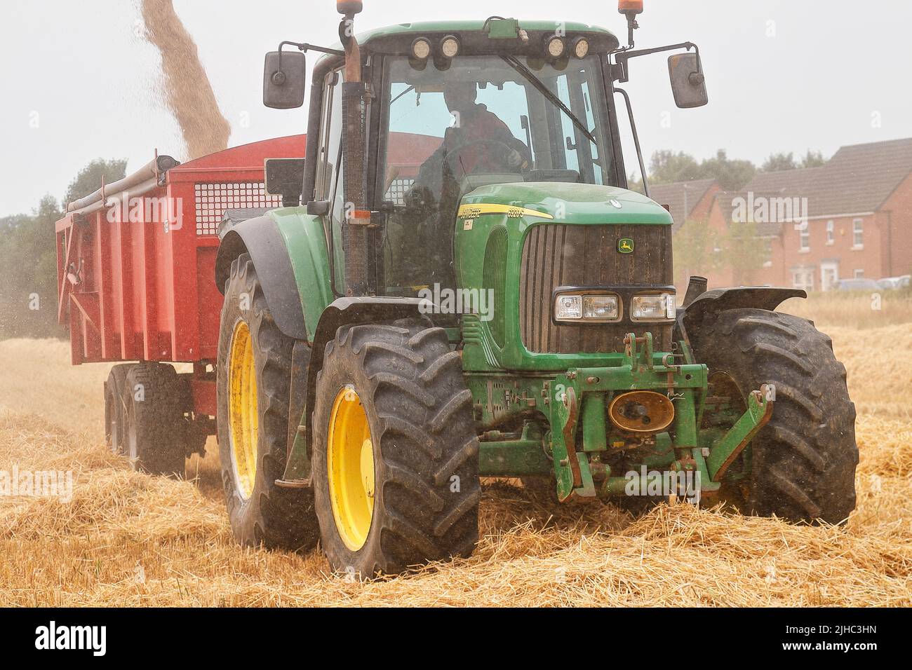 Une moissonneuse-batteuse Claas Lexion 440 charge un tracteur John Deere 6920S avec de l'orge Banque D'Images