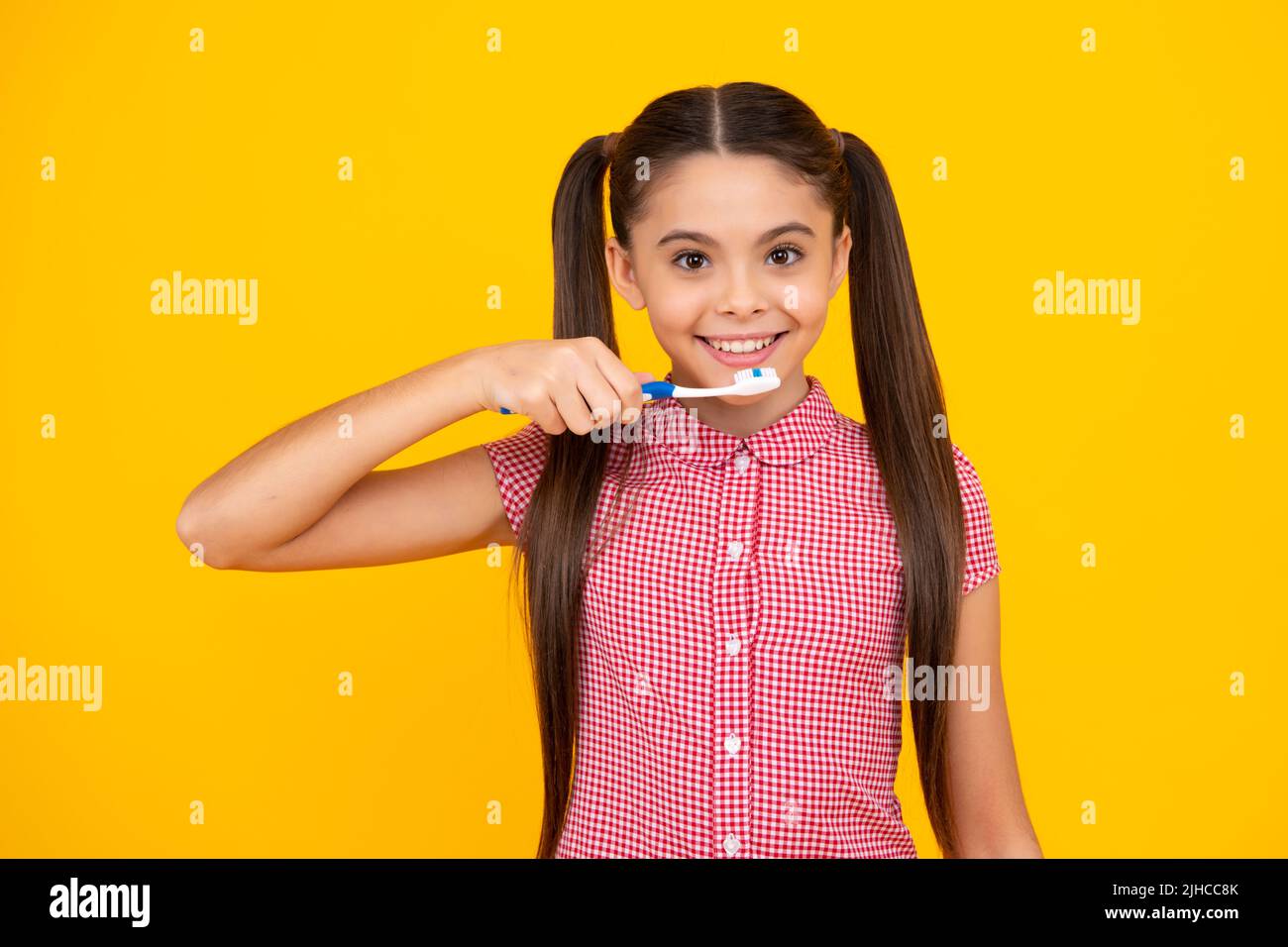 Une adolescente se brossant les dents sur un fond jaune isolé. Brosse à dents d'hygiène quotidienne pour adolescents, routine du matin. Soins dentaires soins buccaux Banque D'Images