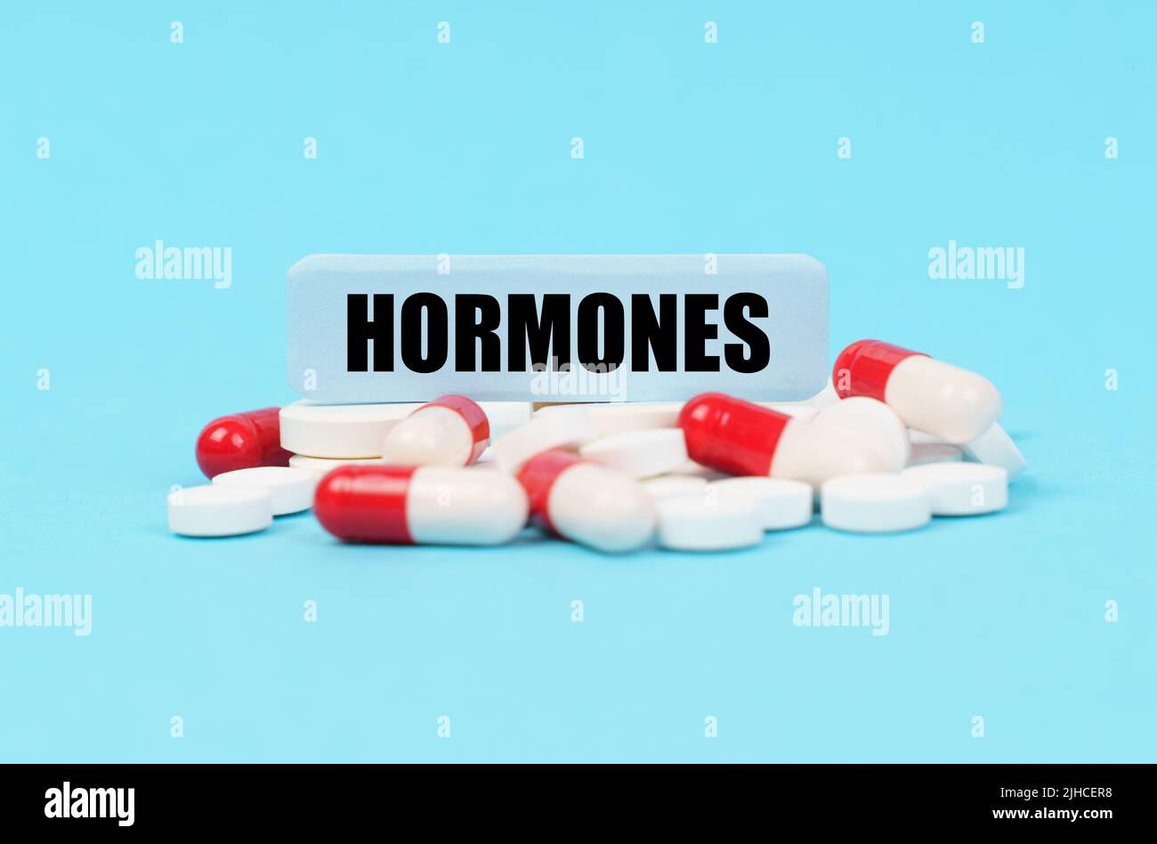 Concept médical. Sur la surface bleue des pilules, des capsules et une assiette avec l'inscription - HORMONES Banque D'Images