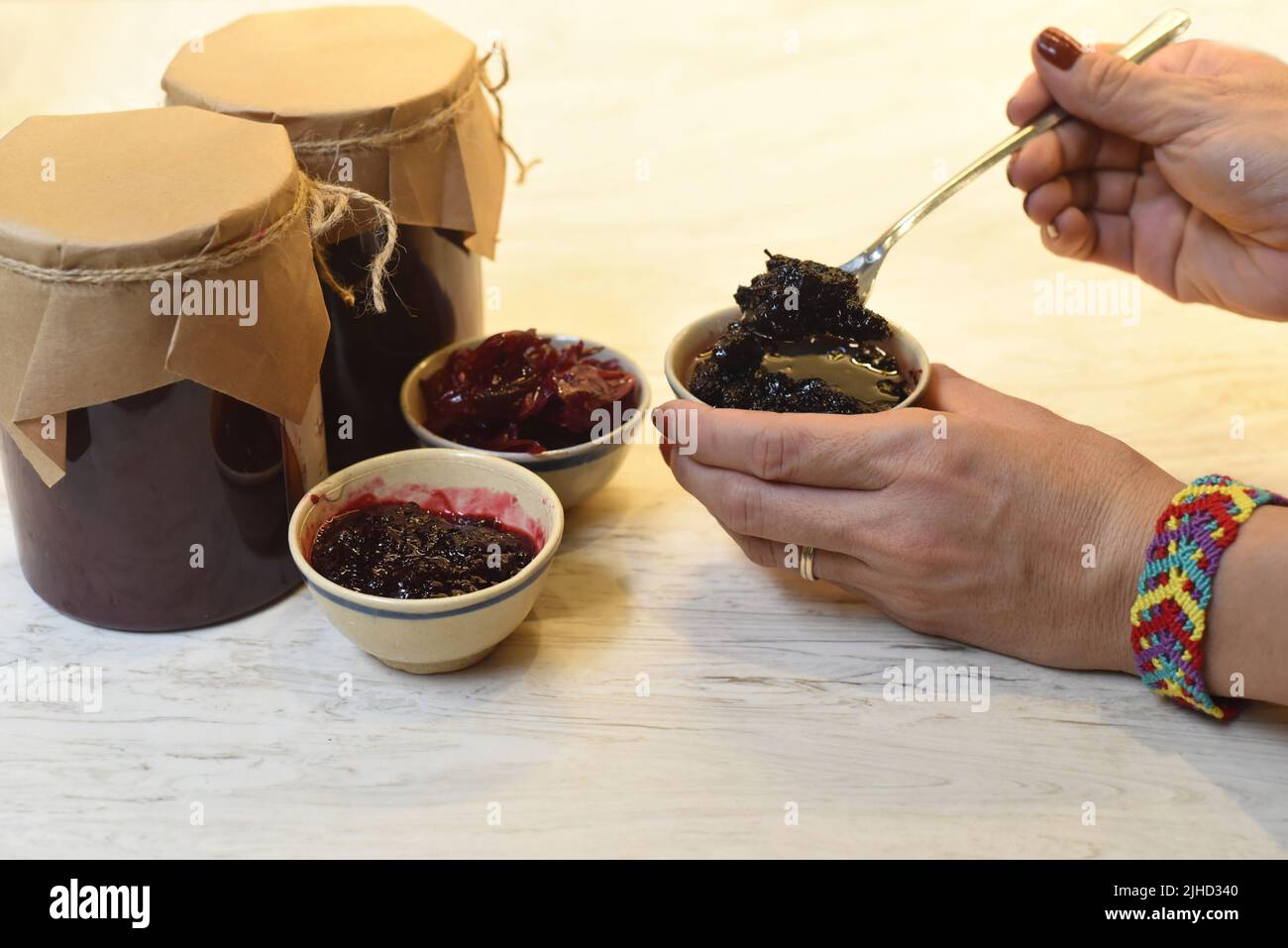 Une main servant de la confiture de mûres maison dans de petits bols en pots Banque D'Images