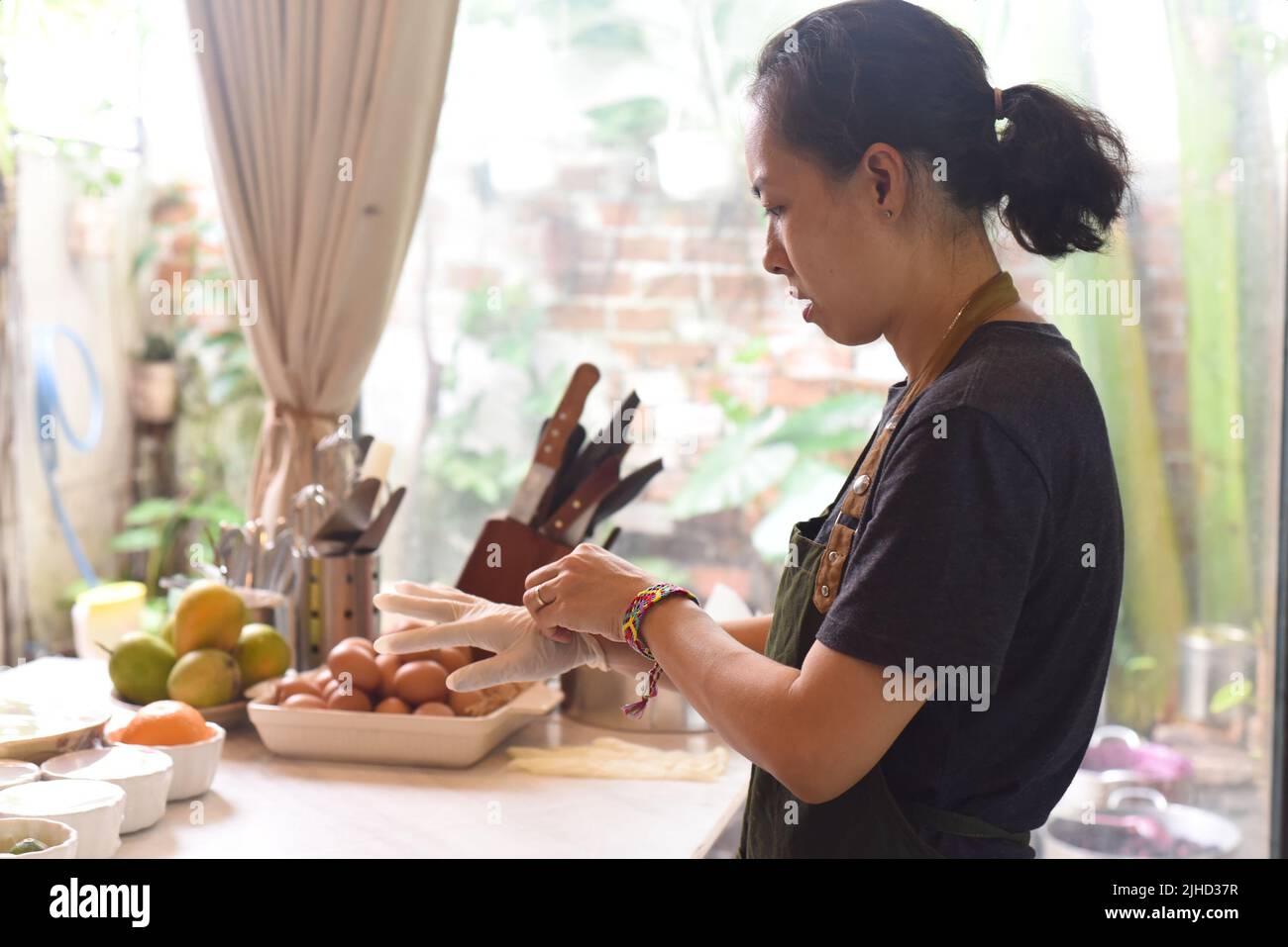 Femme asiatique serveuse prenant des gants de caoutchouc après la cuisson Banque D'Images