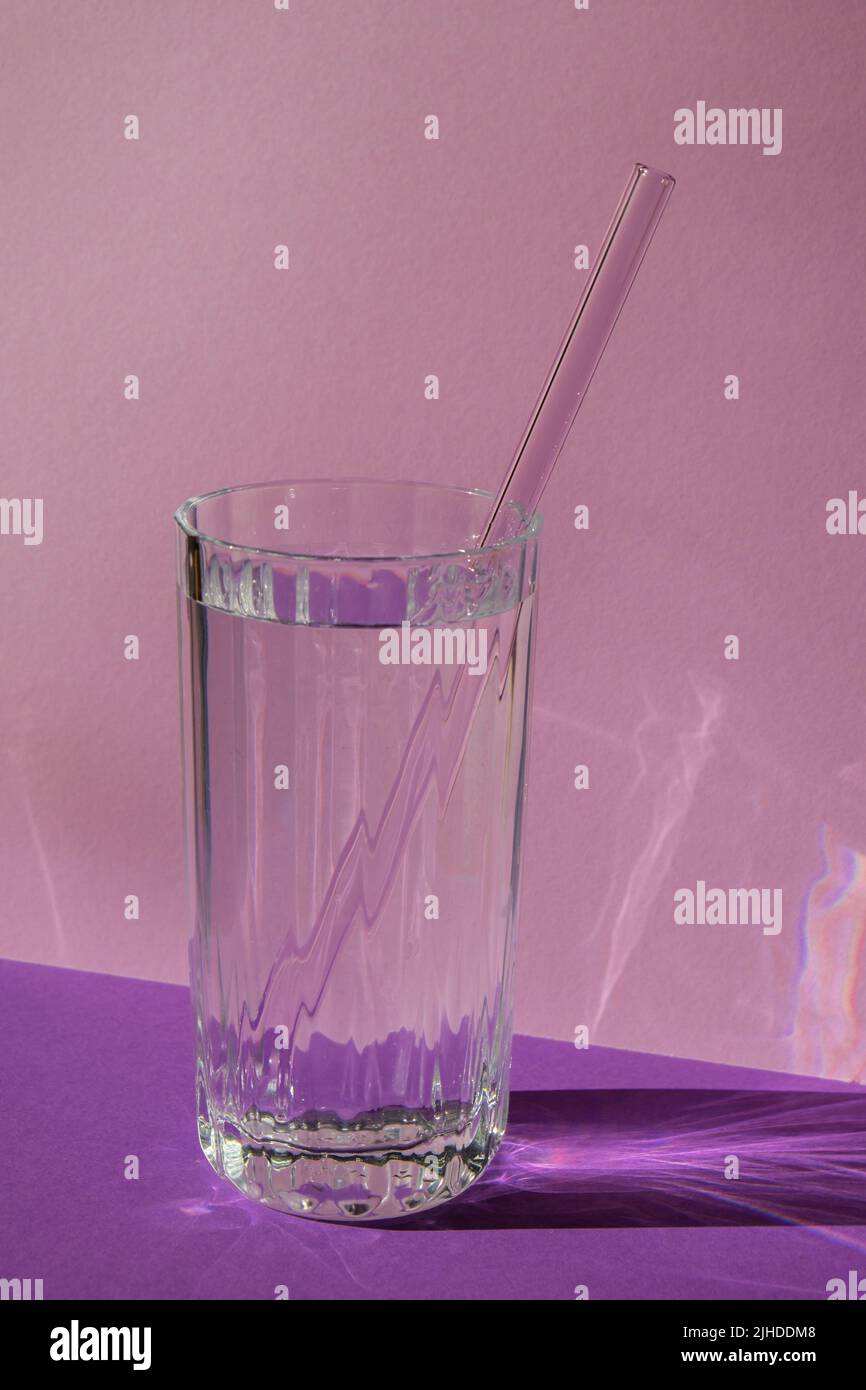 Pailles en verre réutilisables en verre avec eau sur fond violet violet ensemble de pailles écologiques avec brosse de nettoyage. Concept sans déchets, sans plastique. Style de vie durable. Vie sans déchets peu de déchets Banque D'Images