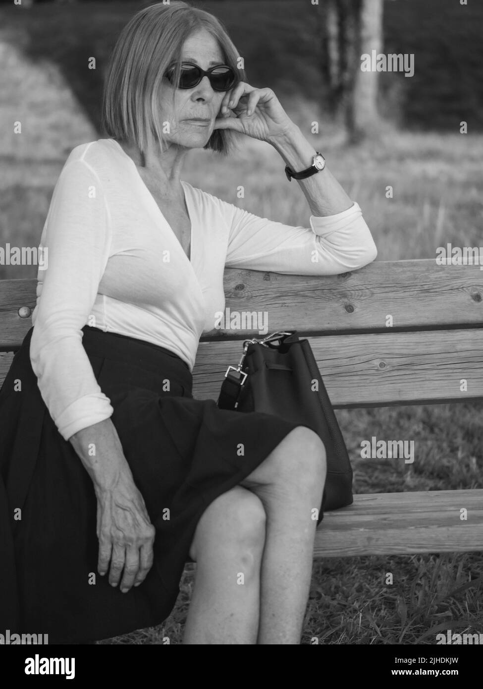 senior tenue élégante dame habillé blaka dn blanc portant des lunettes de soleil appréciant la nature en été Banque D'Images