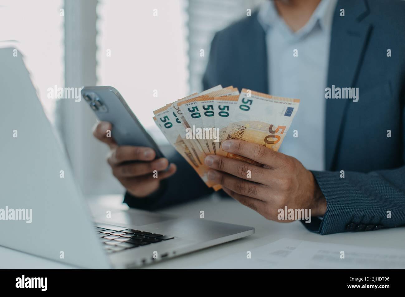 Homme d'affaires avec de l'argent euro entre ses mains travaille sur un clavier d'ordinateur au bureau, gros plan Banque D'Images