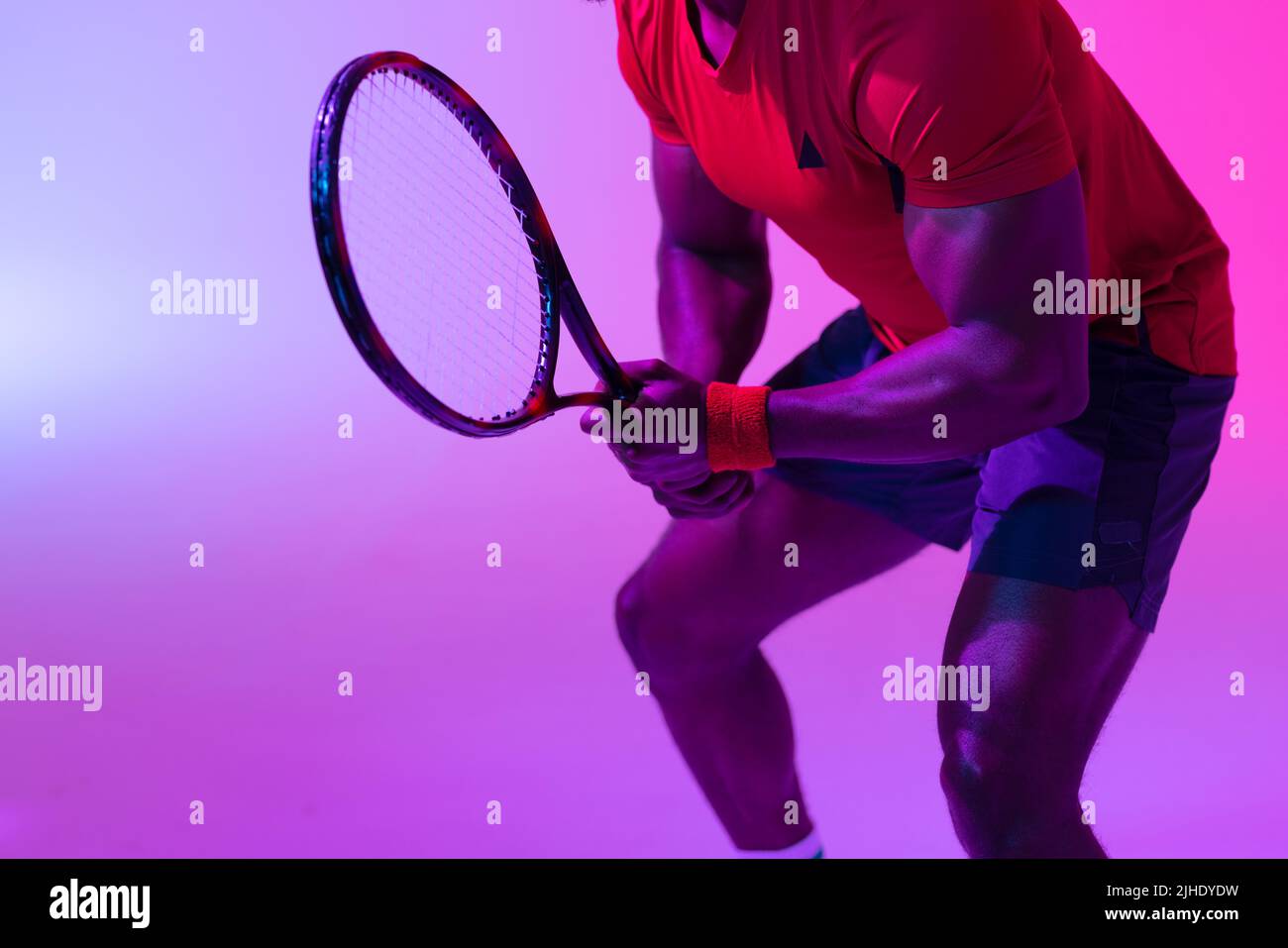 Image de la section médiane d'un joueur de tennis afro-américain dans un éclairage violet fluo Banque D'Images
