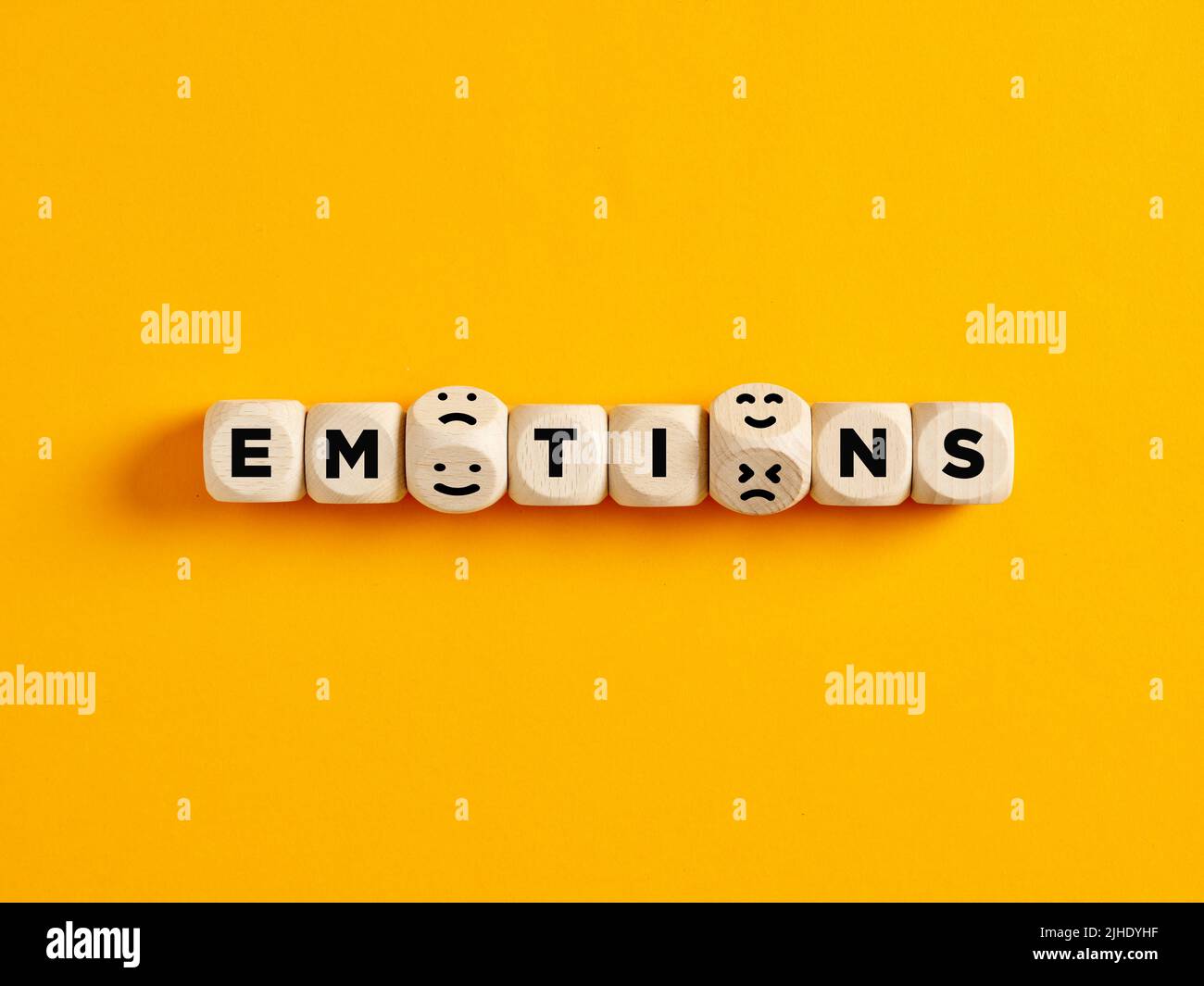 Cubes en bois avec le mot émotions avec des icônes d'émoticônes sur fond jaune. Variété d'émotions ou d'attitudes négatives et positives dans la vie ou le busine Banque D'Images