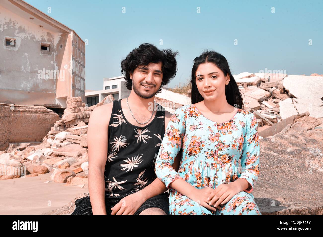 Jeune couple heureux assis sur un rocher et posant avec le sourire Banque D'Images