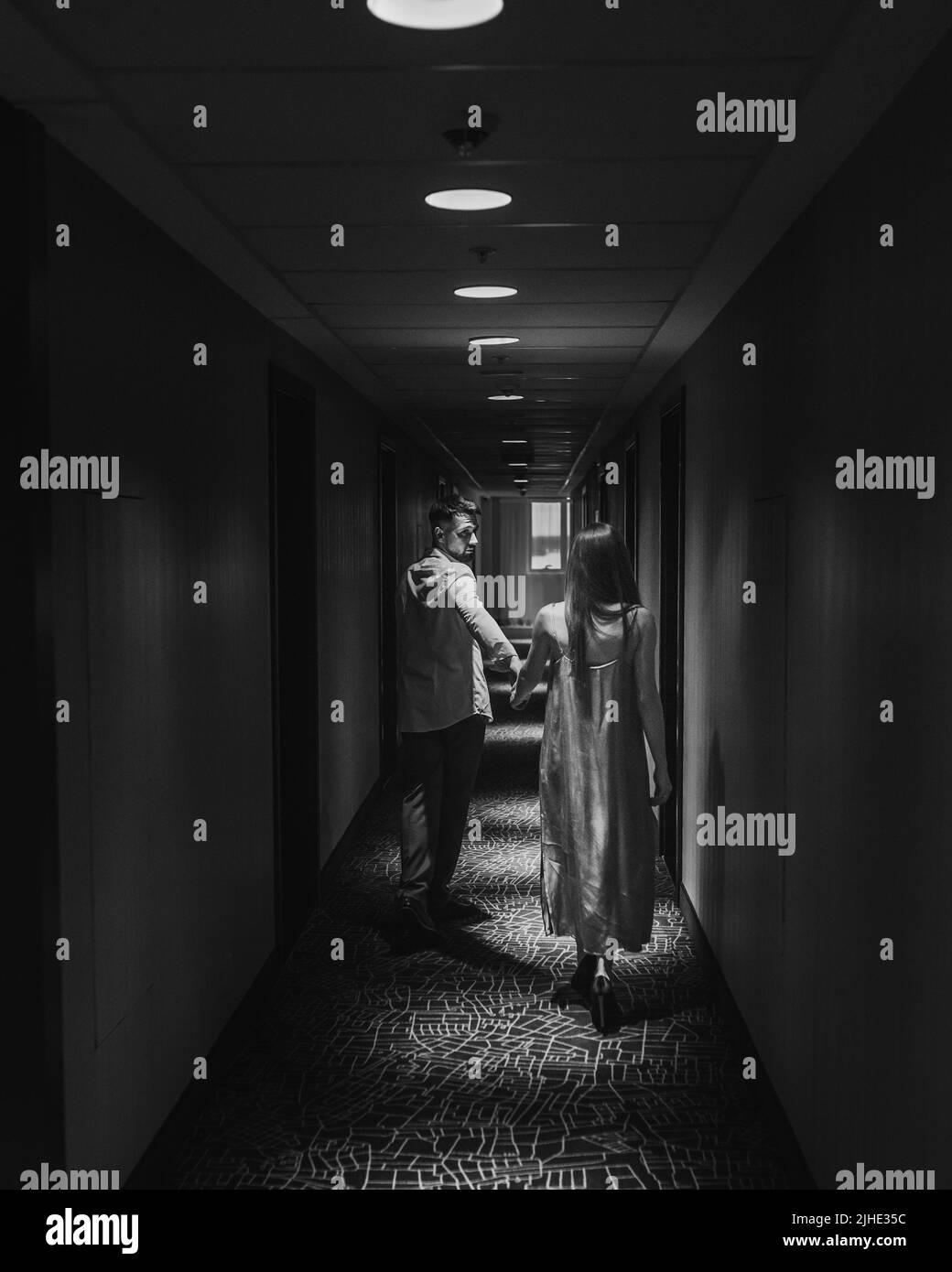 Couple amoureux debout et embrassant dans le couloir de l'hôtel en marchant le long du couloir de l'hôtel Banque D'Images