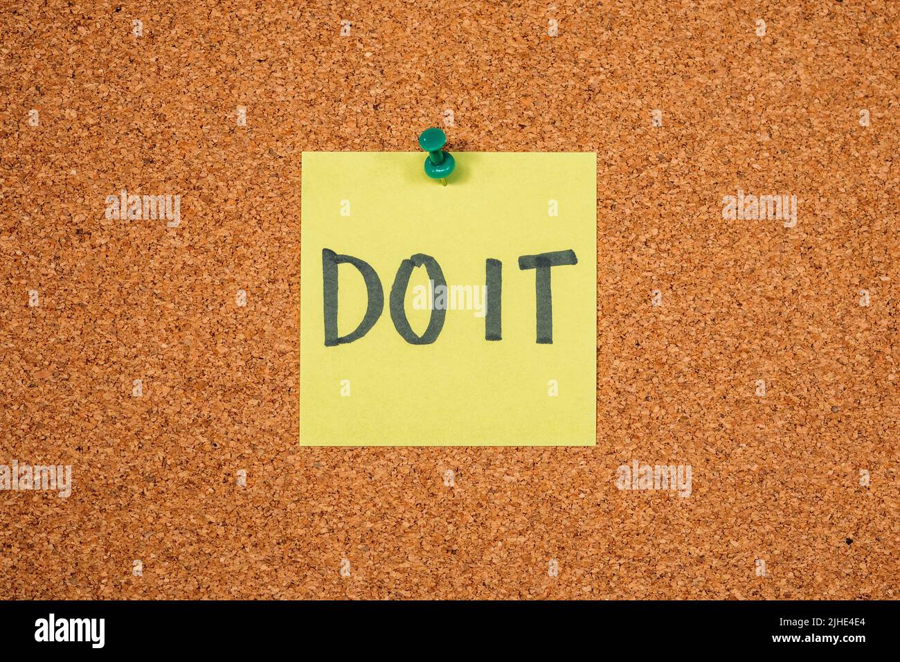 Note autocollante jaune sur un tableau en liège avec le mot « Do IT » Banque D'Images