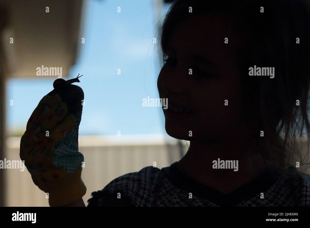 Une silhouette d'une petite fille tenant un petit escargot Banque D'Images