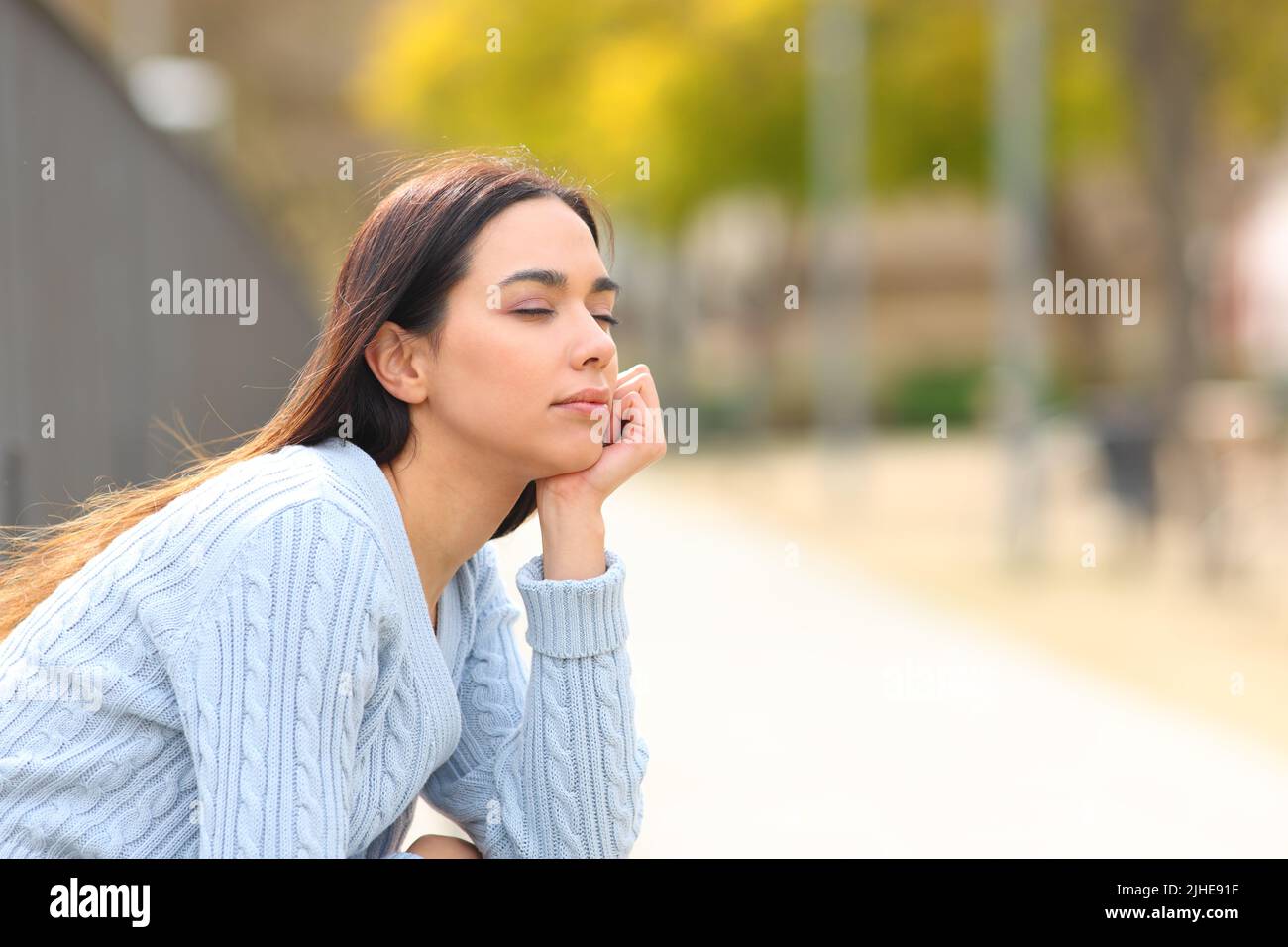 Femme détendue se reposant avec les yeux fermés assis dans un parc Banque D'Images