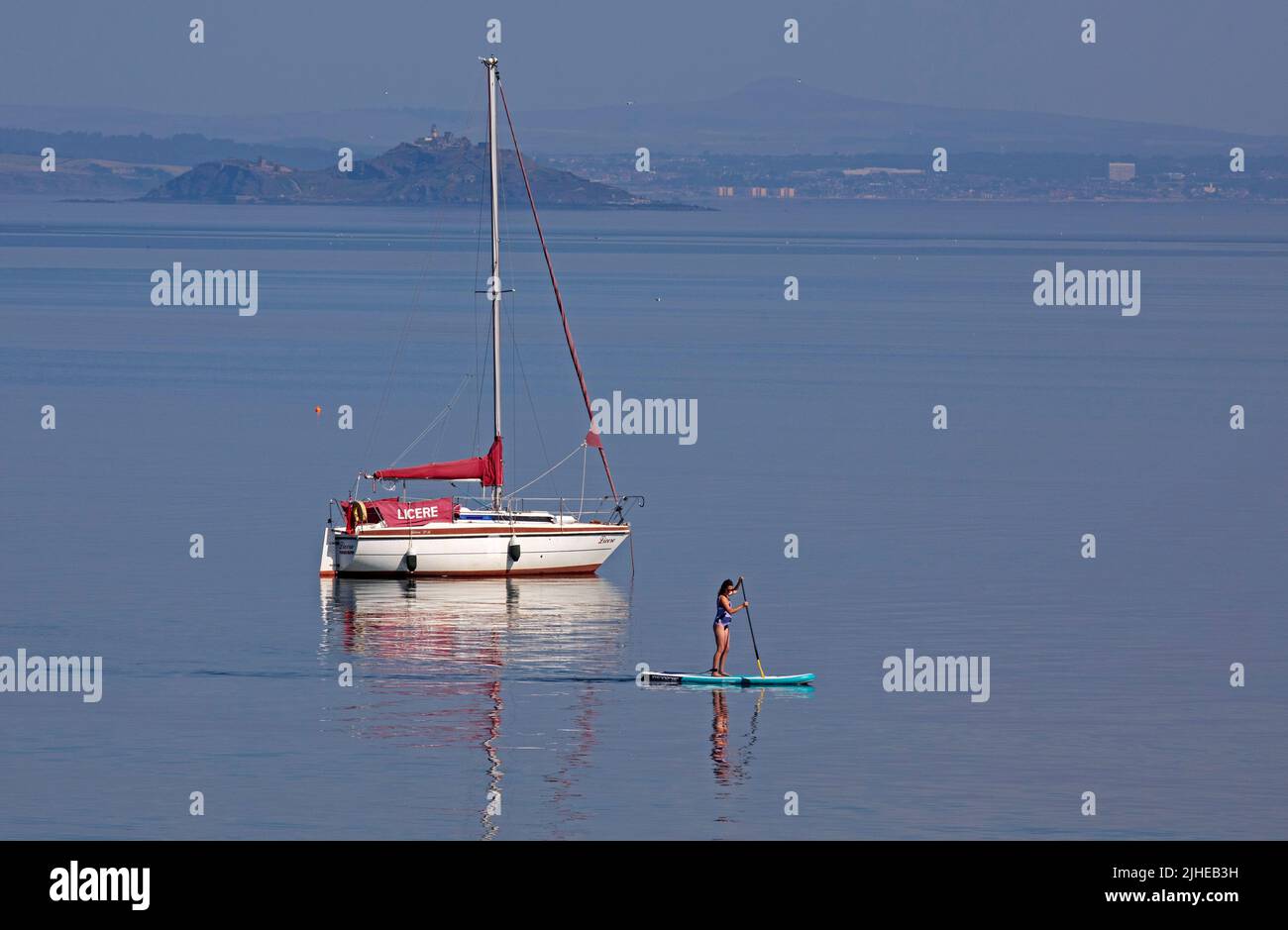 Portobello, Édimbourg, Écosse, Royaume-Uni. 18th juillet 2022. La température augmente avec 23 degrés centigrade seulement after10am, a augmenté jusqu'à 29 degrés centigrade en 1pm. Photo : paddleboarder cool appréciant le calme Firth of Forth avec Inchkeith Island en arrière-plan. Banque D'Images