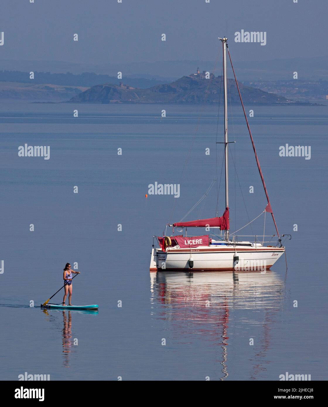 Portobello, Édimbourg, Écosse, Royaume-Uni. 18th juillet 2022. La température augmente avec 23 degrés centigrade seulement after10am, a augmenté jusqu'à 29 degrés centigrade en 1pm. Photo : paddleboarder cool appréciant le calme Firth of Forth avec Inchkeith Island en arrière-plan. Banque D'Images