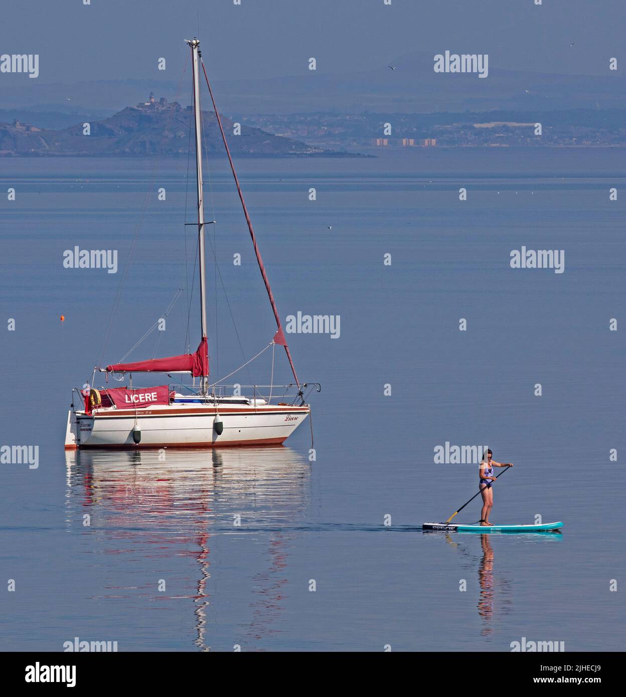 Portobello, Édimbourg, Écosse, Royaume-Uni. 18th juillet 2022. La température augmente avec 23 degrés centigrade seulement after10am, a augmenté jusqu'à 29 degrés centigrade en 1pm. Photo : paddleboarder cool appréciant le calme Firth of Forth avec Inchkeith Island en arrière-plan. Banque D'Images