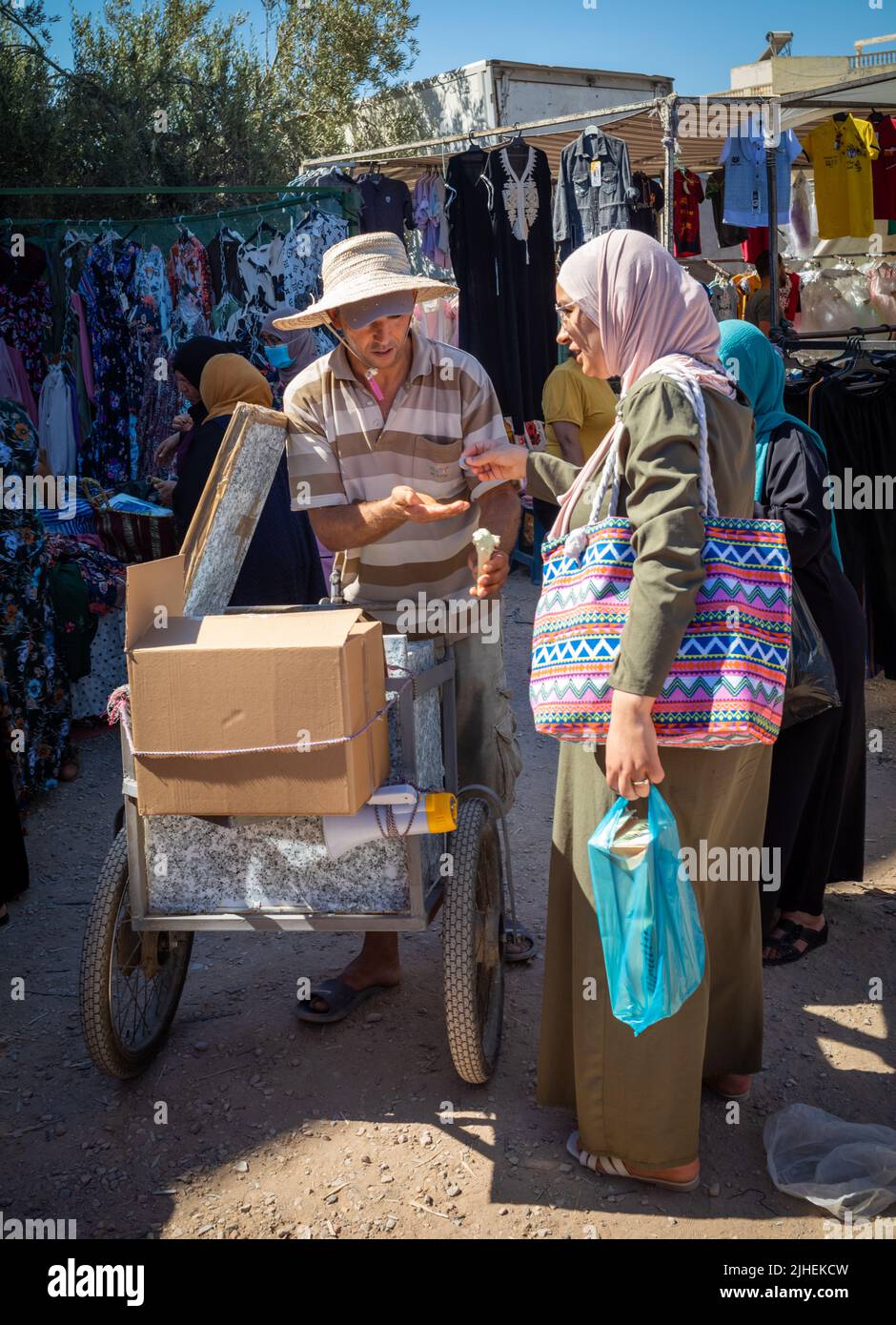 Une femme achète une glace à un vendeur du Sunday Souk, un marché hebdomadaire à Sousse, en Tunisie. Banque D'Images