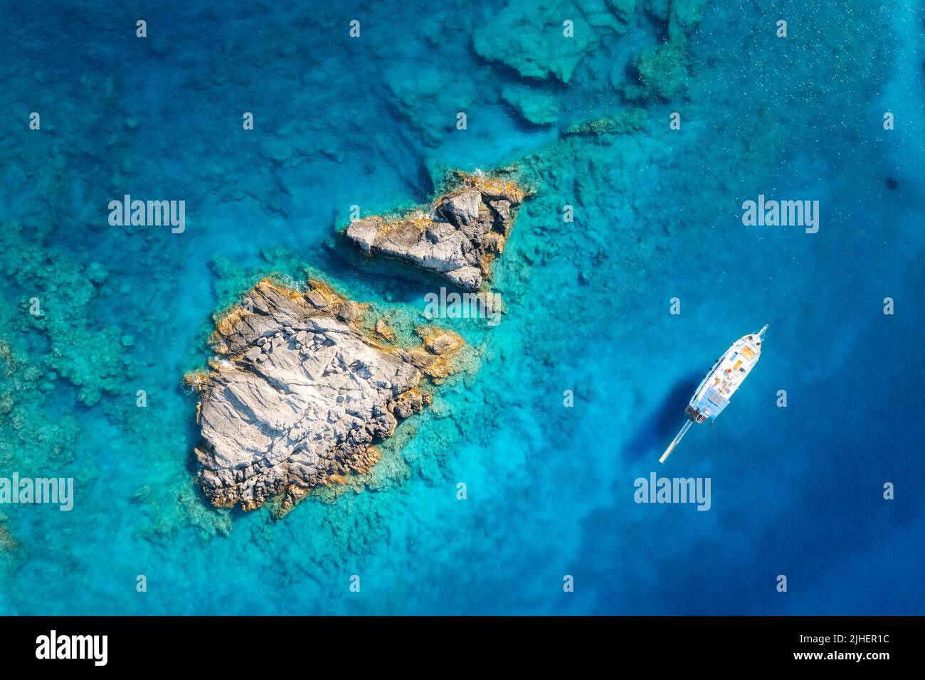 Vue aérienne du magnifique yacht sur la mer et des rochers au coucher du soleil Banque D'Images