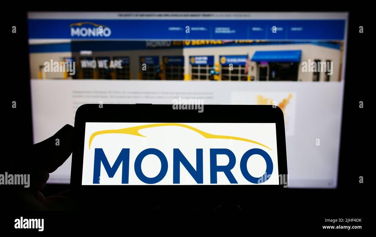 Personne tenant un smartphone avec le logo de la société de service automobile américaine Monro Inc. À l'écran devant le site Web. Mise au point sur l'affichage du téléphone. Banque D'Images