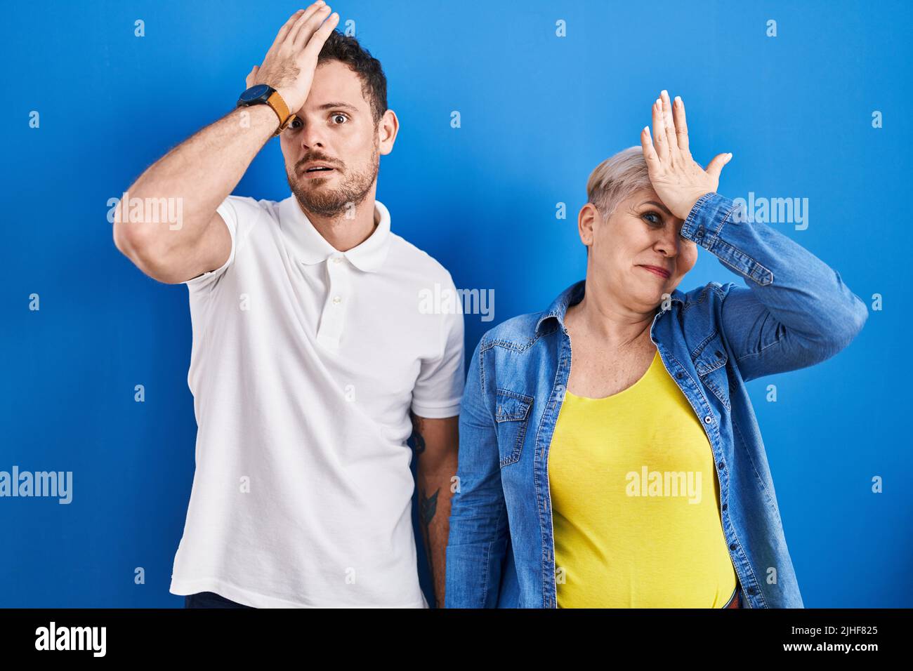 Jeune mère brésilienne et fils debout sur fond bleu surpris par la main sur la tête pour l'erreur, souvenez-vous de l'erreur. oublié, mauvais concept de mémoire. Banque D'Images Jeune mère brésilienne et fils debout sur fond bleu surpris par la main sur la tête pour l'erreur, souvenez-vous de l'erreur. oublié, mauvais concept de mémoire. Banque D'Images