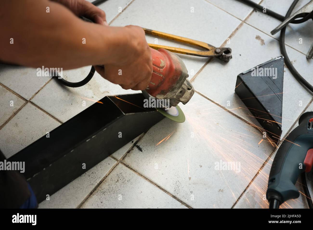 L'entrepreneur utilise une meuleuse électrique pour décorer le point de soudage de l'acier. Banque D'Images