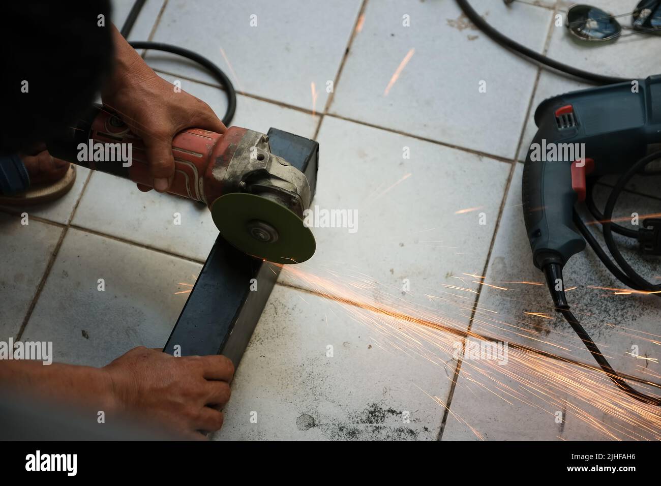 L'entrepreneur utilise une meuleuse électrique pour décorer le point de soudage de l'acier. Banque D'Images