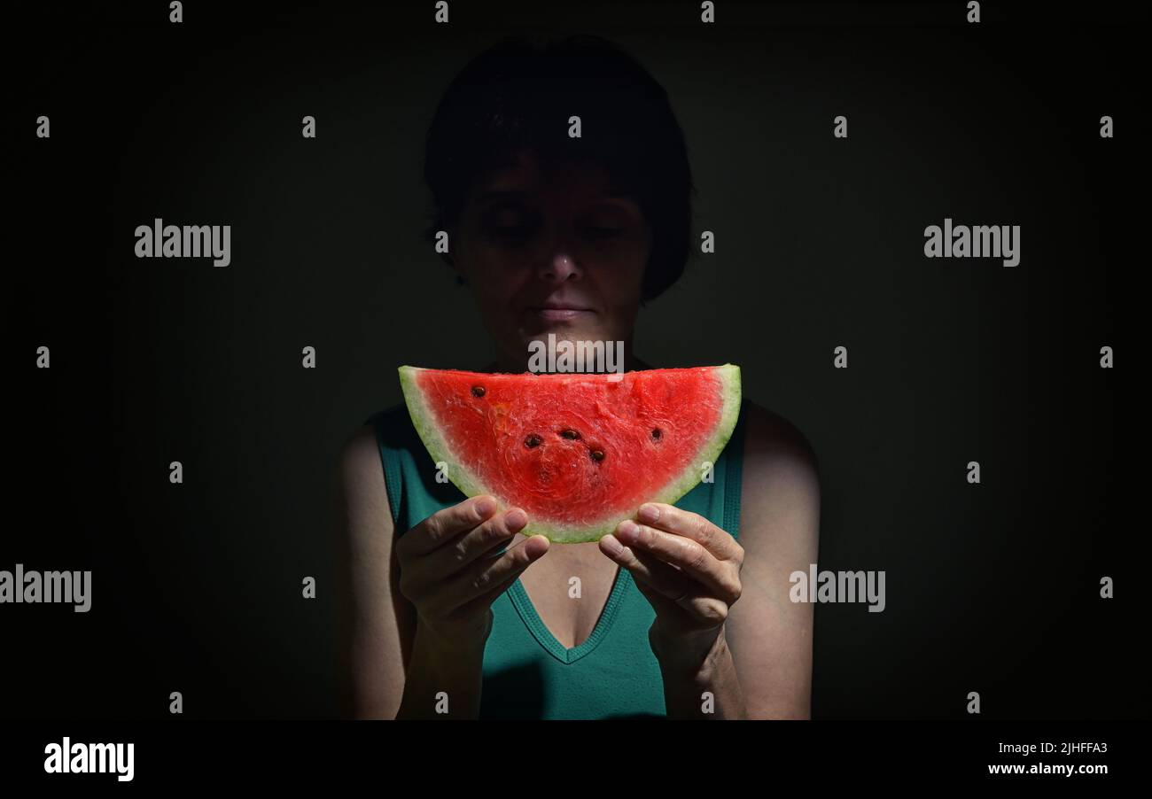 Femme tenant une tranche d'Une pastèque rouge dans Studio Banque D'Images