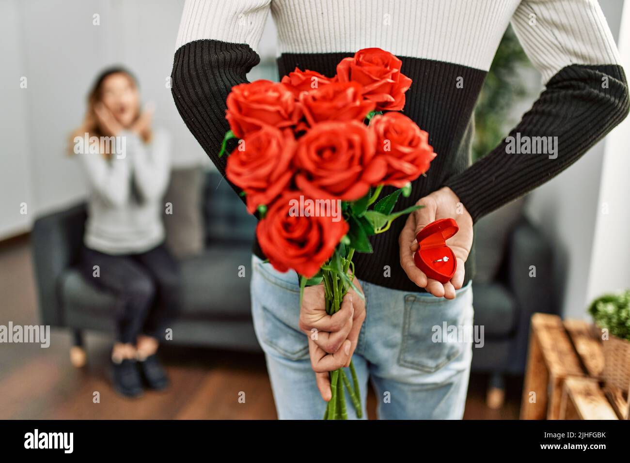 Homme femme suprising avec bouquet de roses et anneau d'engagement à la maison. Banque D'Images