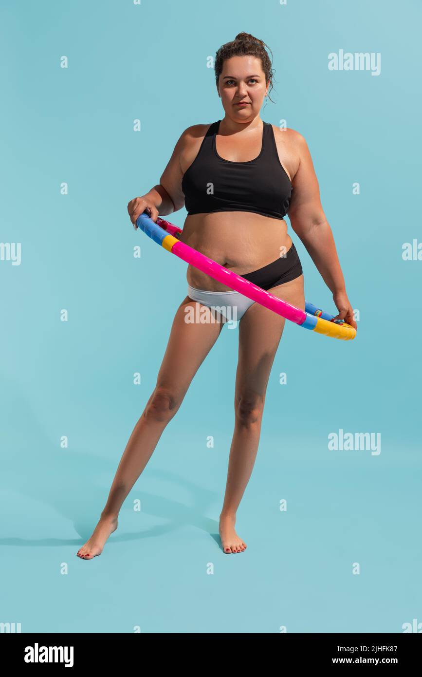 Collage conceptuel avec jeune femme plus-taille avec des jambes minces faisant des exercices avec hula Hoop. Perte de poids, forme physique, alimentation saine, motivation Banque D'Images