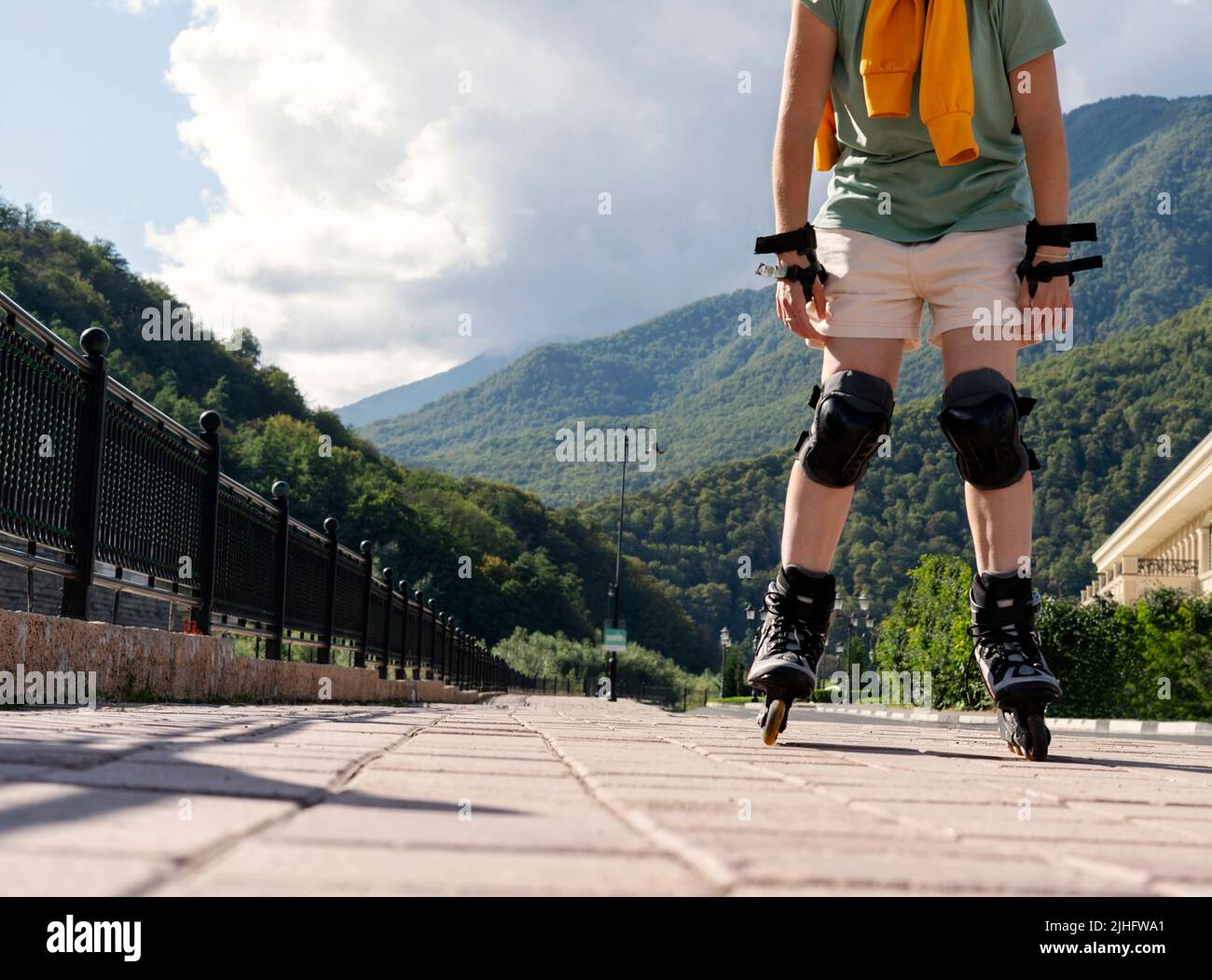 femme en équipement de protection sur patins à roulettes le long d'un remblai en été vie active, activités de plein air, patinage à roulettes sans visage Banque D'Images