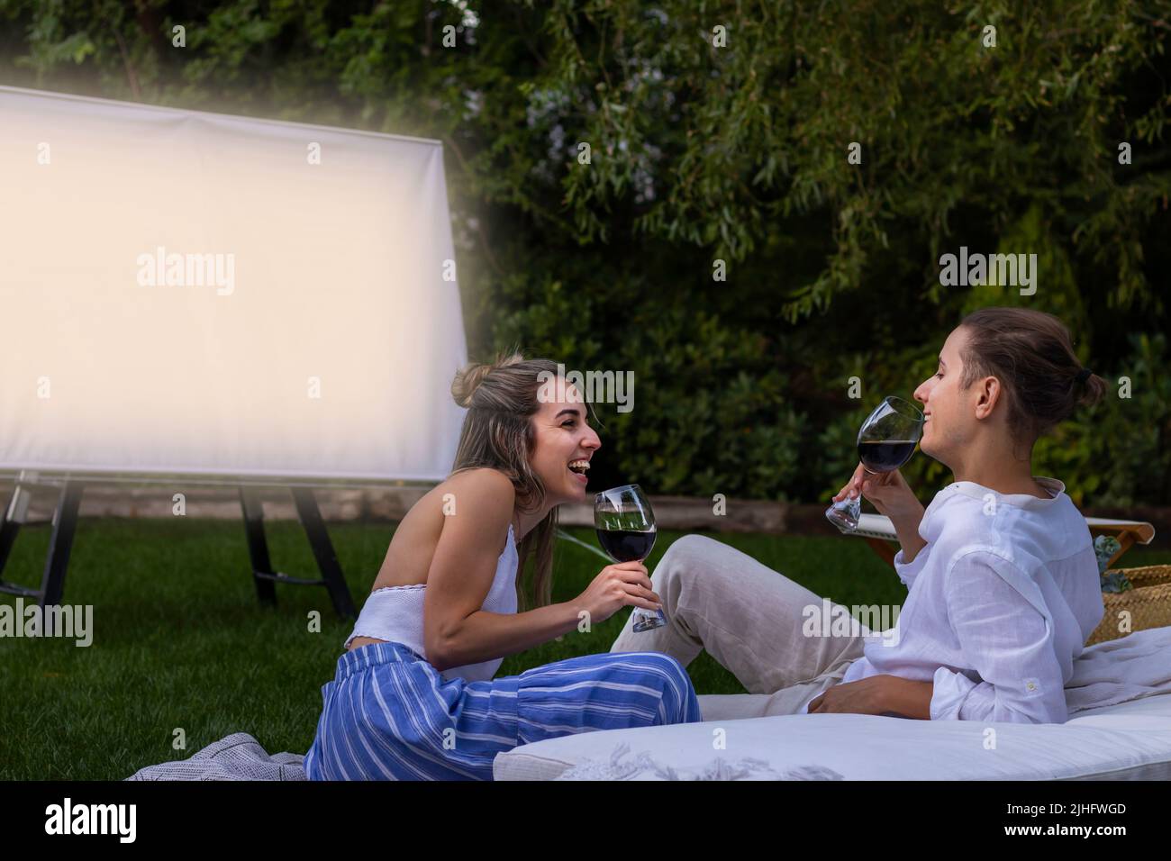 Dans l'amour, les jeunes couples rient et s'amusent tout en buvant du vin rouge et en regardant un film comme une date Banque D'Images
